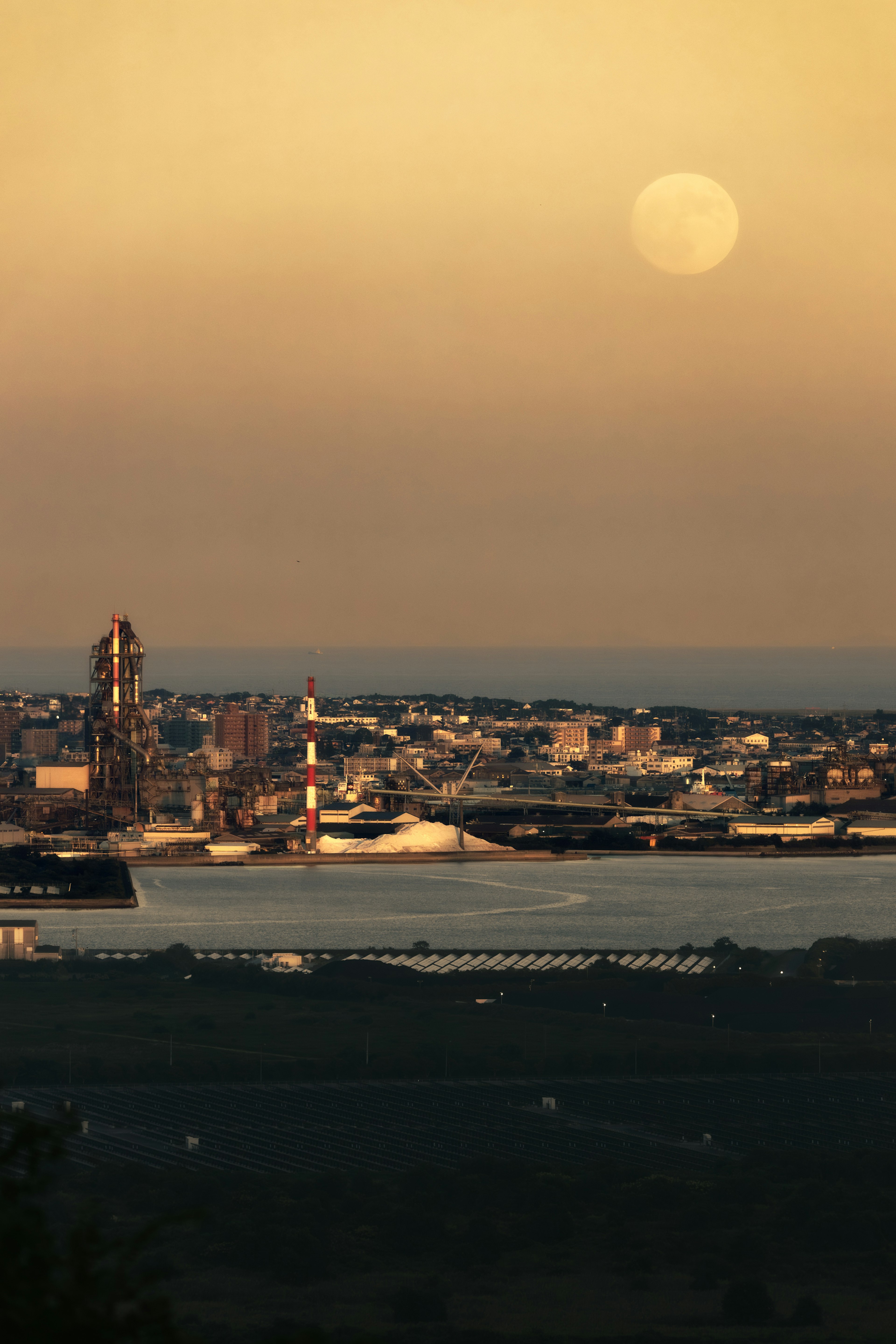 Paesaggio urbano industriale al crepuscolo con una grande luna