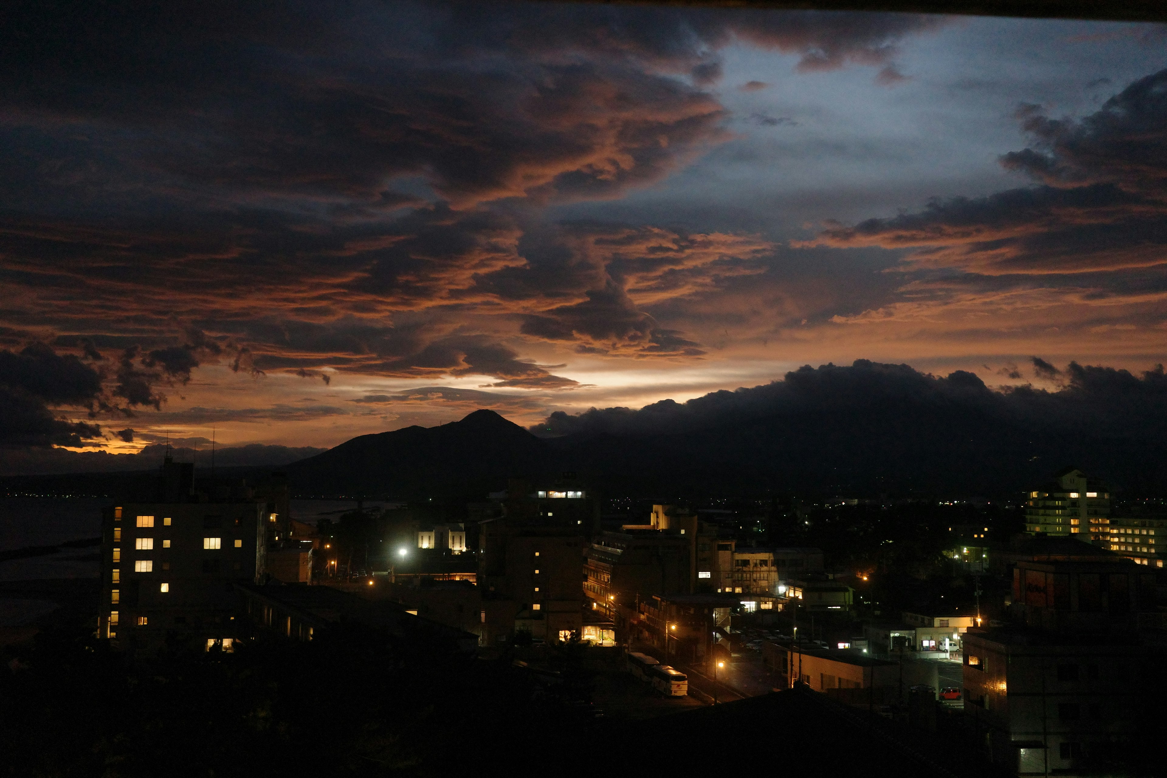 Paesaggio urbano al crepuscolo con montagne in silhouette e nuvole drammatiche