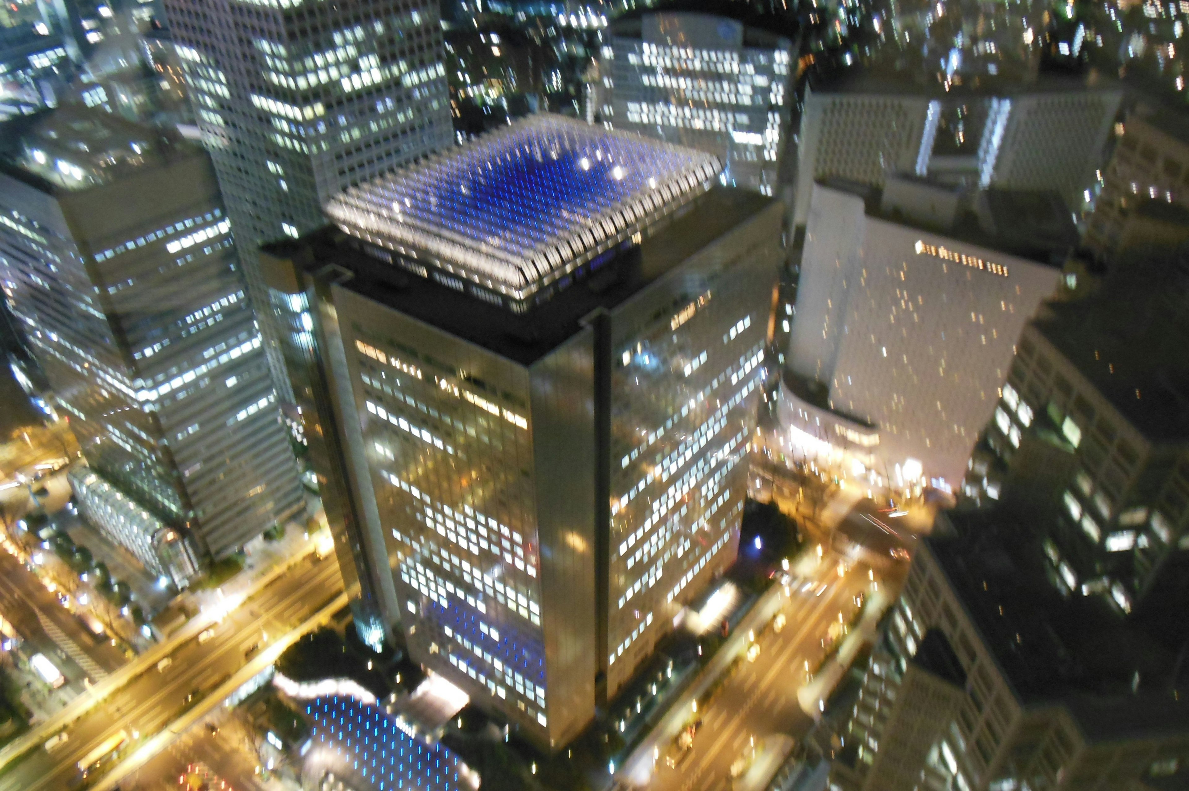 Night cityscape with skyscrapers illuminated windows and a rooftop pool