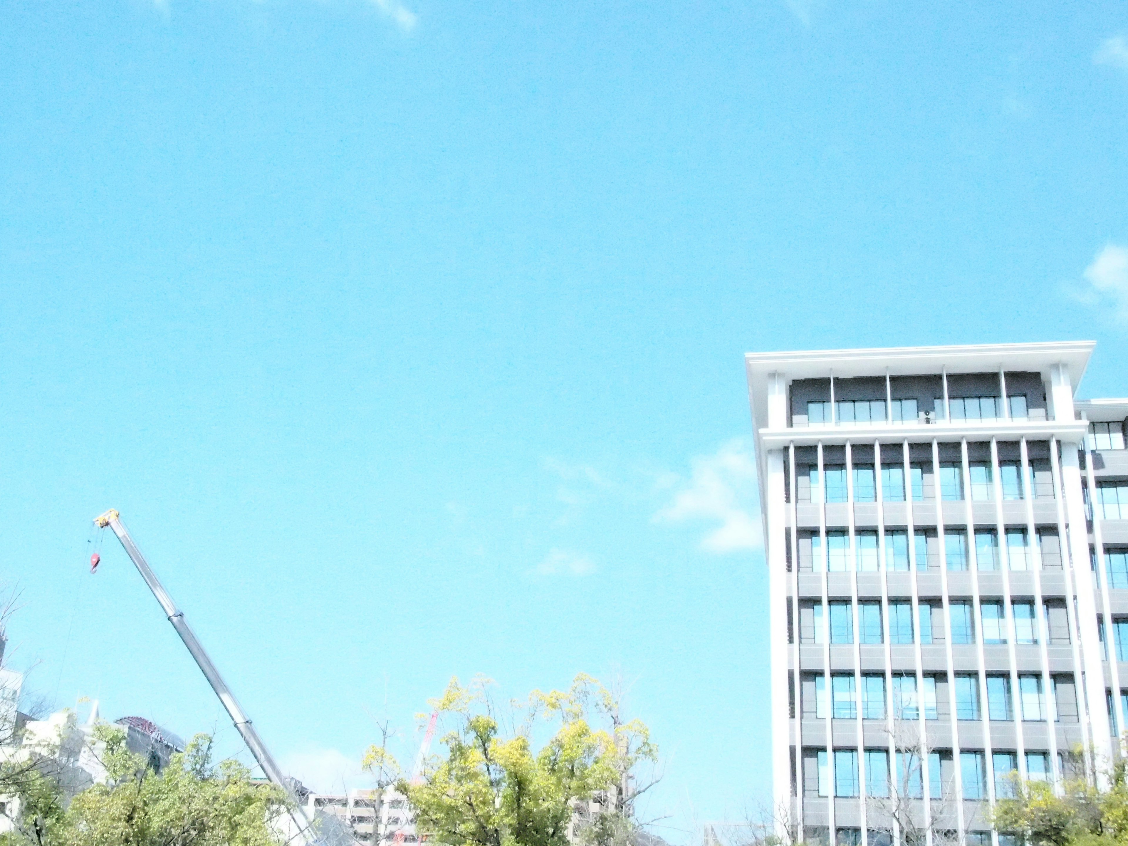 Bangunan modern di bawah langit biru cerah dengan crane