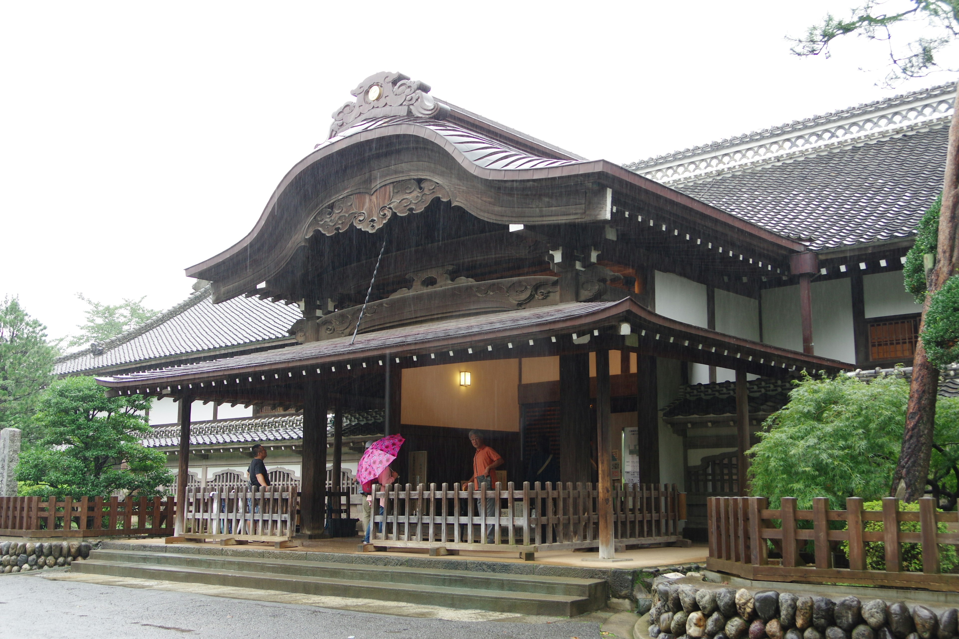 Beautiful exterior of a traditional Japanese building with people holding umbrellas on a rainy day