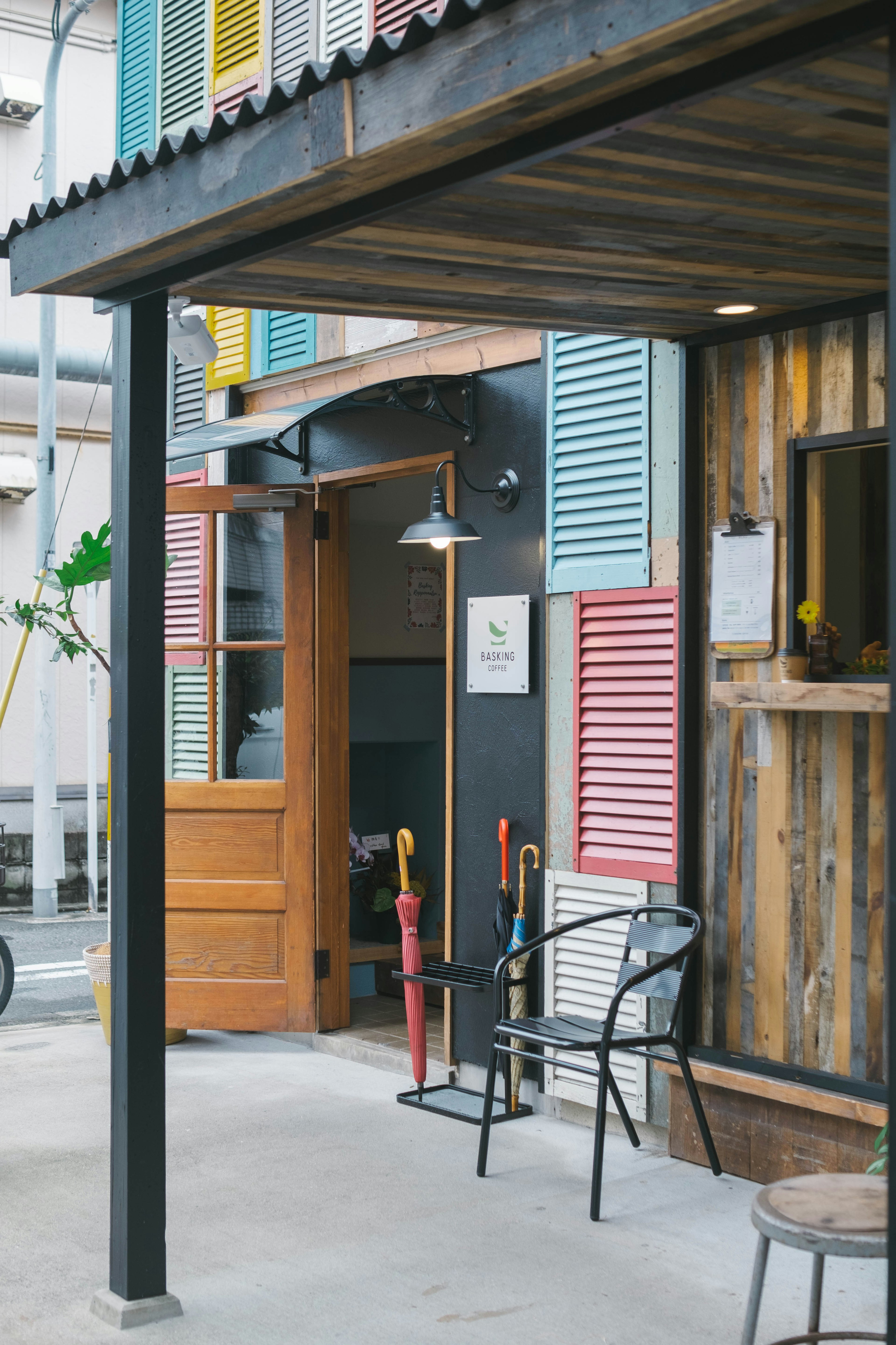 Entrada de café con persianas coloridas y puerta de madera