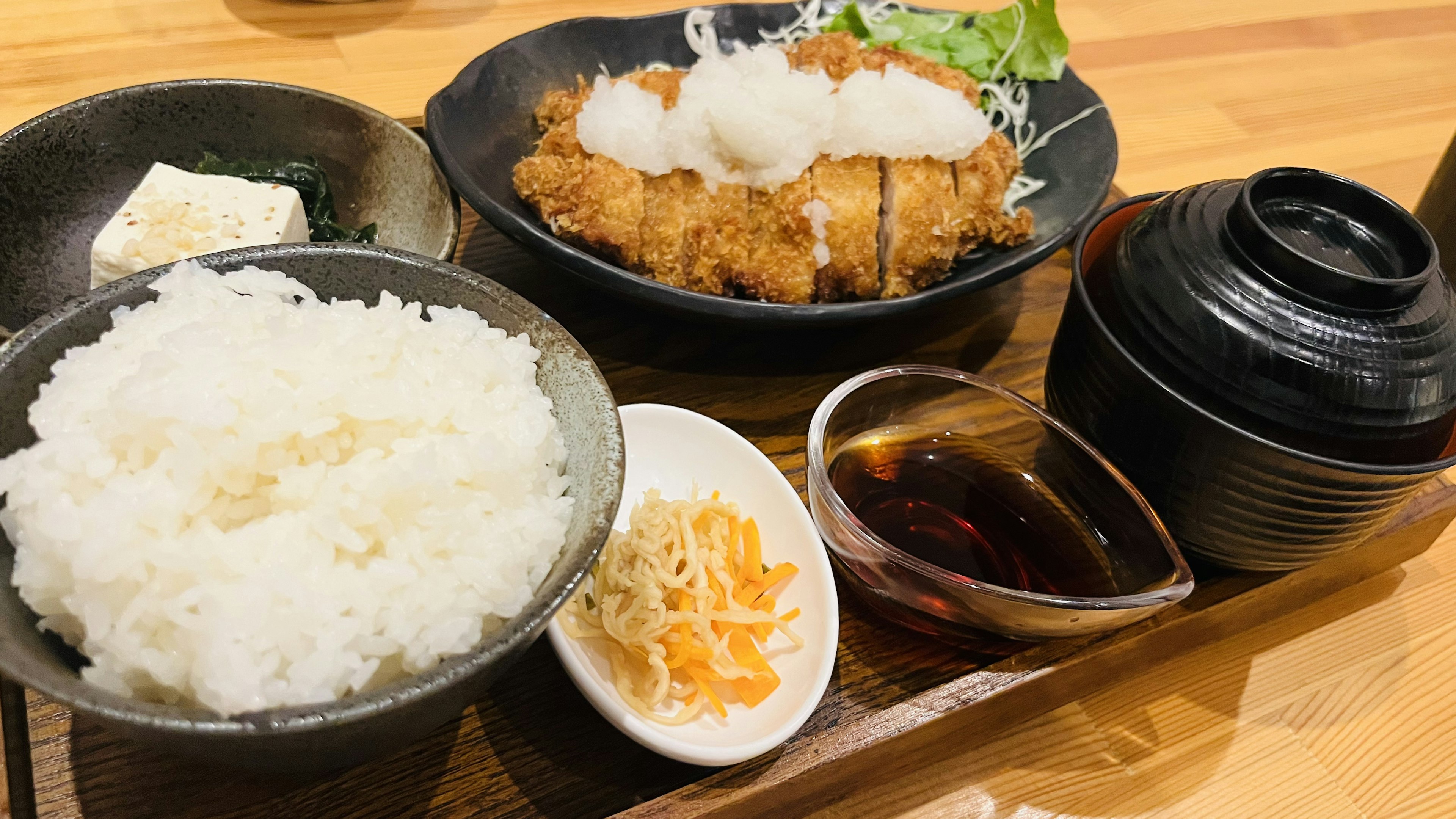 揚げ物のトンカツ、白ご飯、みそ汁、サラダ、漬物が盛り付けられた日本の定食