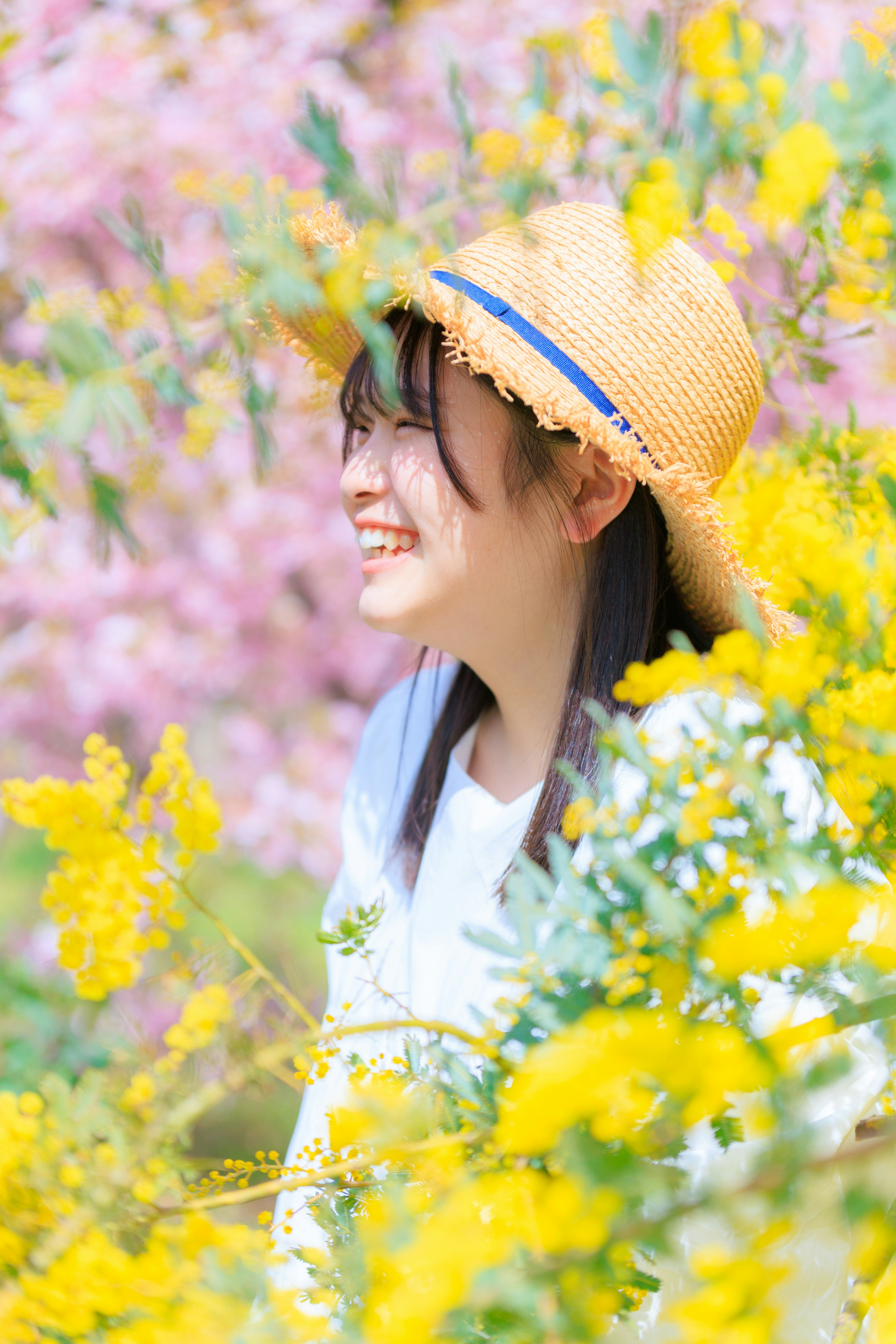 Femme souriante entourée de fleurs jaunes et de fleurs roses