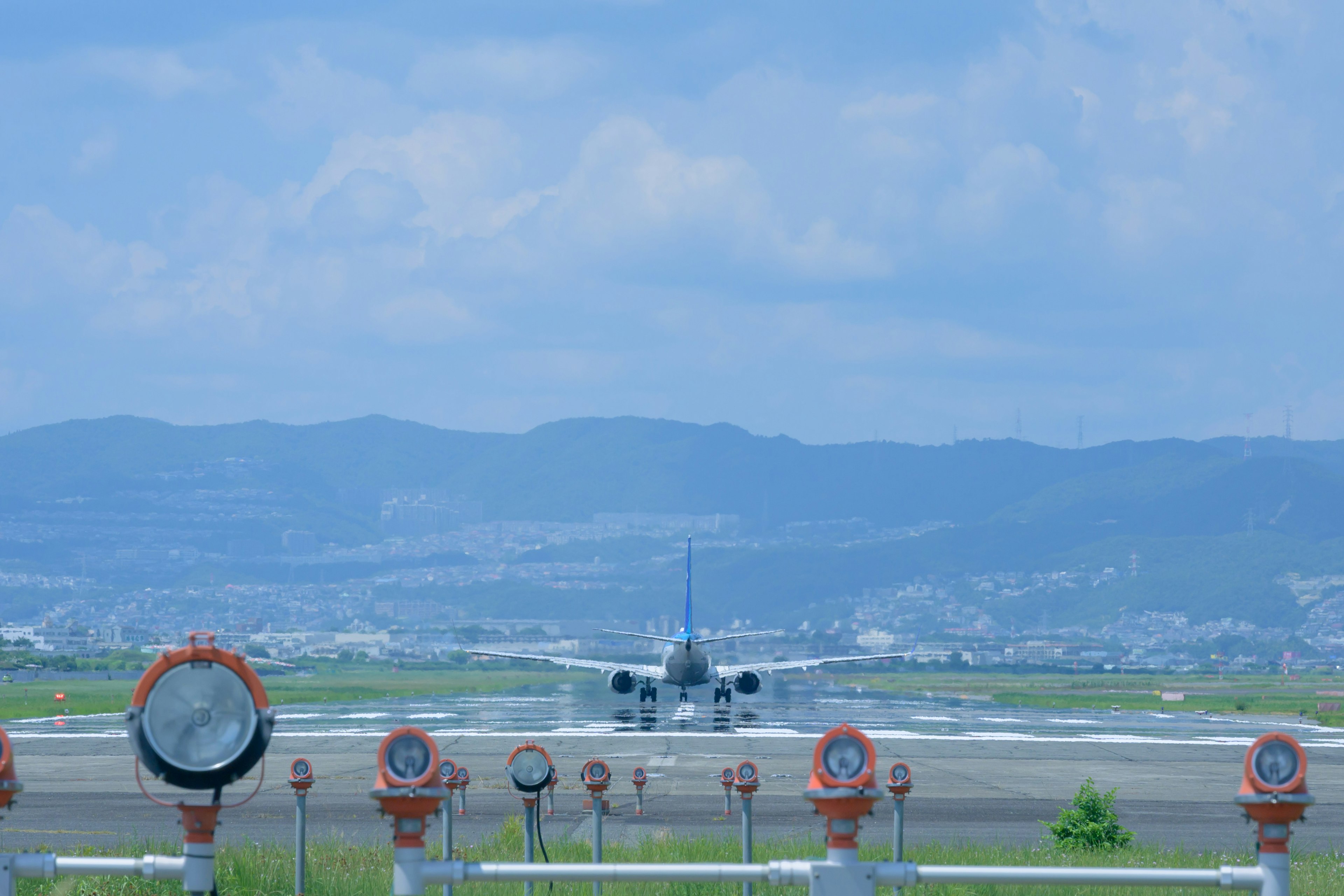 Flugzeug rollt auf der Landebahn mit blauem Himmel und Bergen im Hintergrund