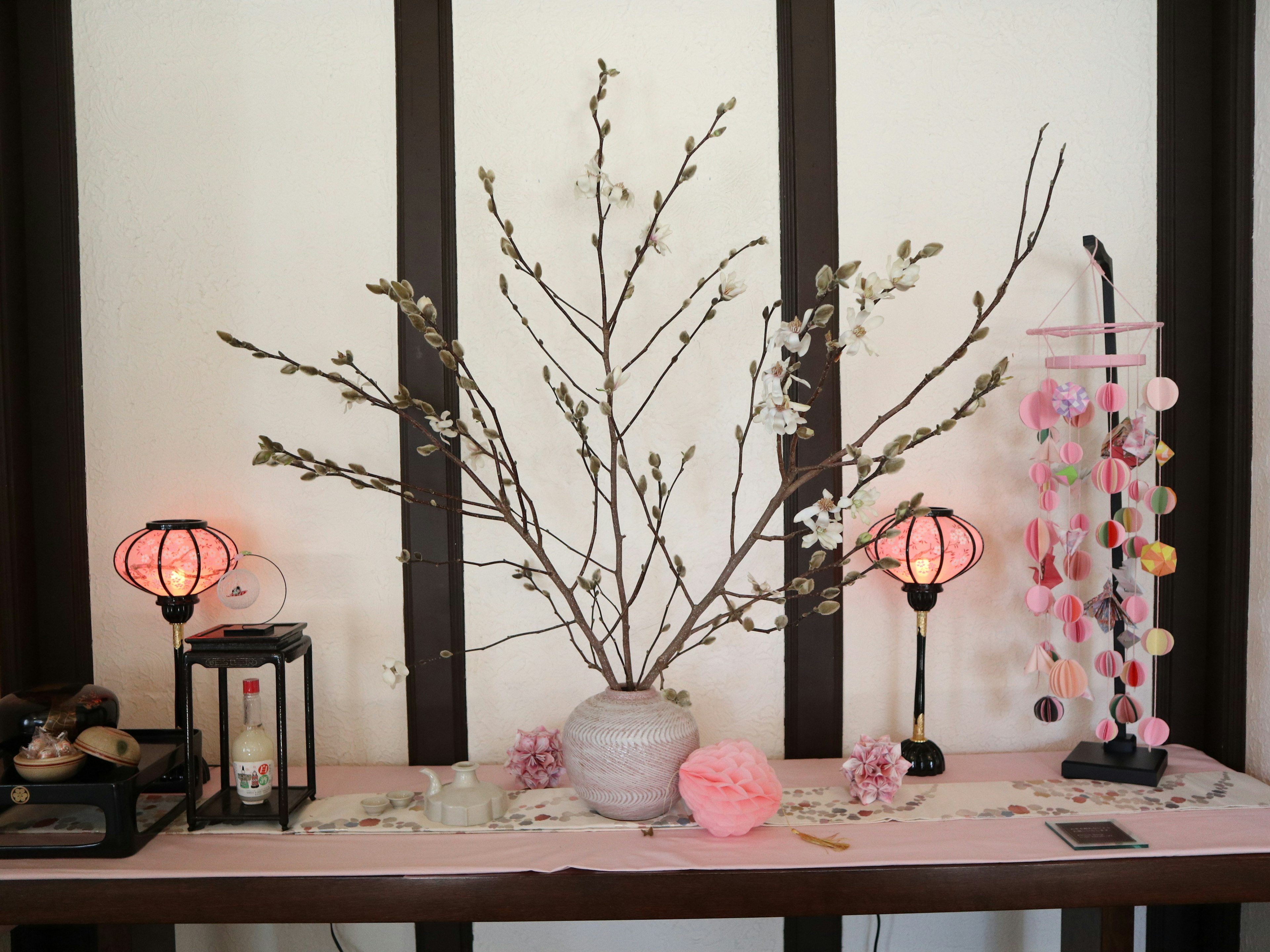 Table décorative avec un vase contenant des branches des lanternes et des ornements colorés dans un style intérieur japonais