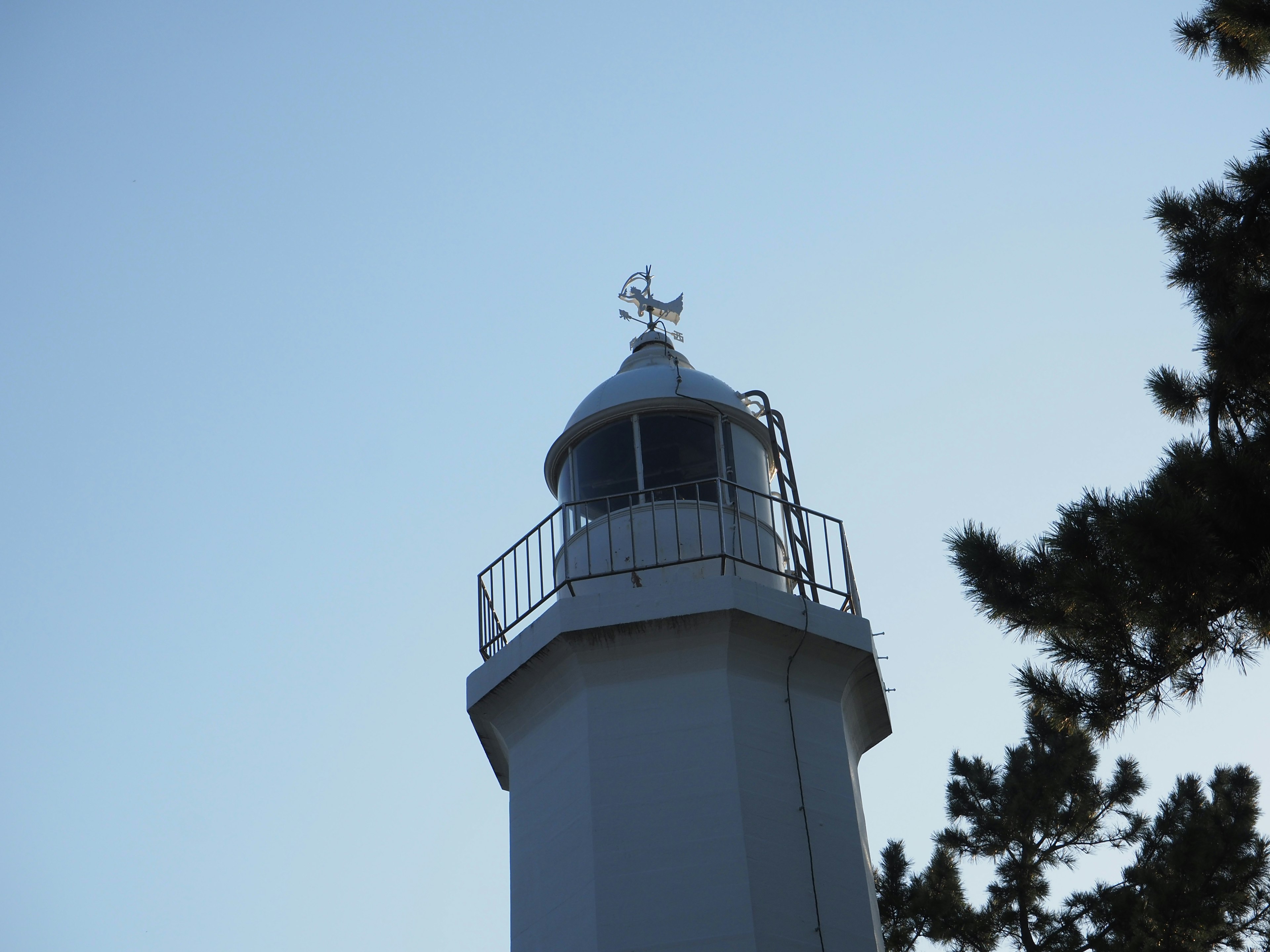 White lighthouse top against a clear blue sky