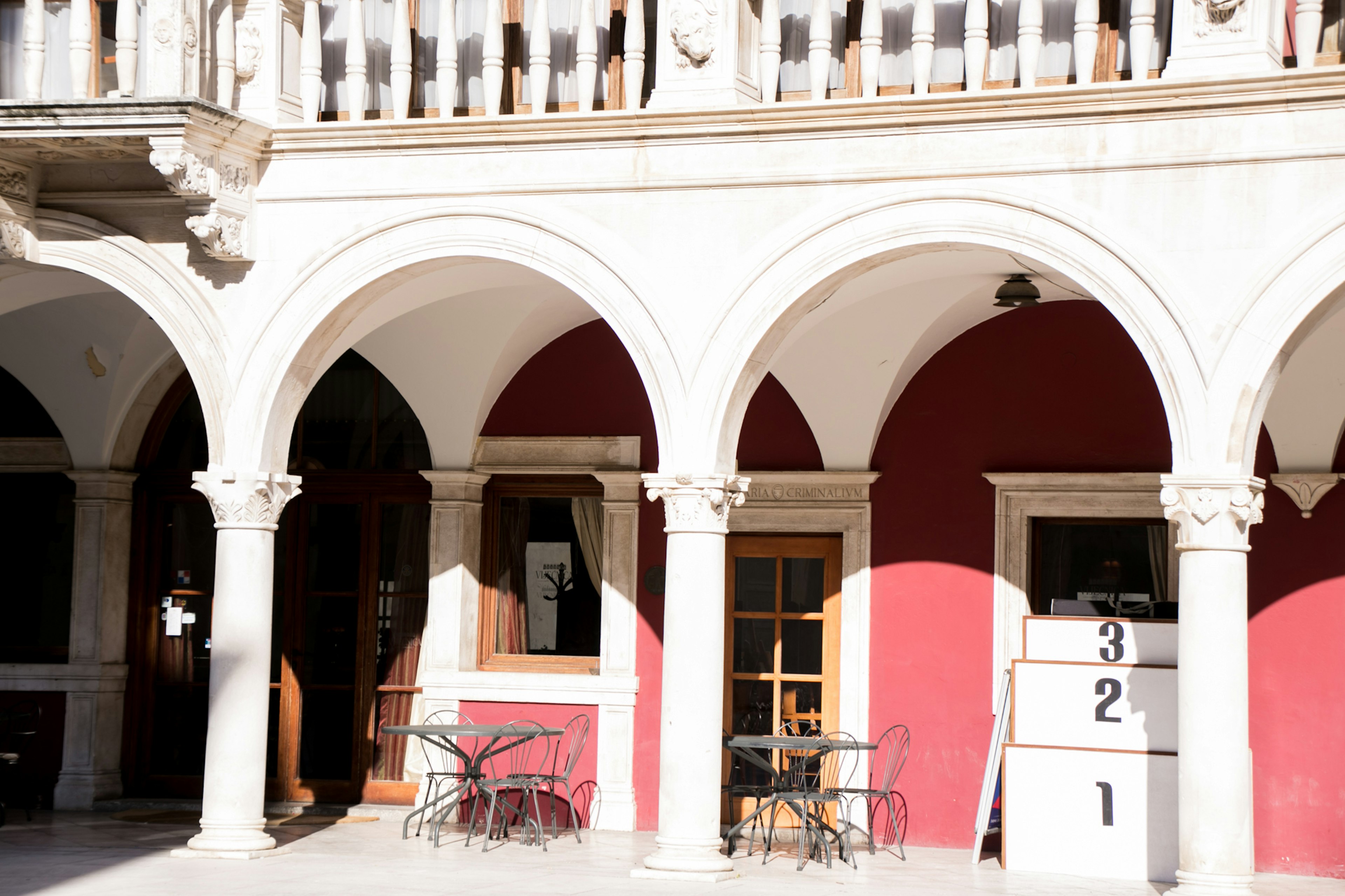 Building exterior featuring arch columns and a red wall