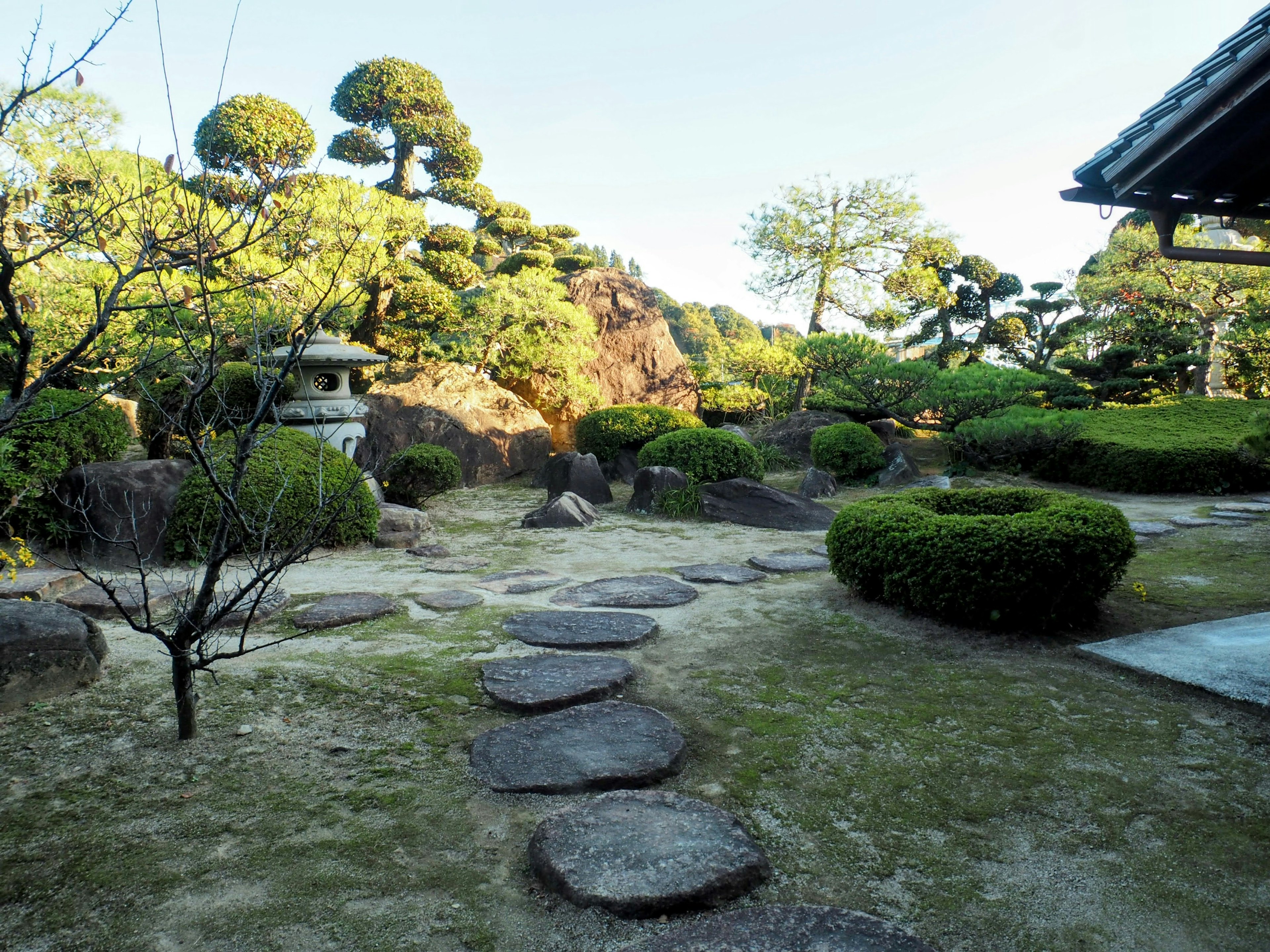 Vista serena di un giardino giapponese con sentiero di pietra e vegetazione lussureggiante