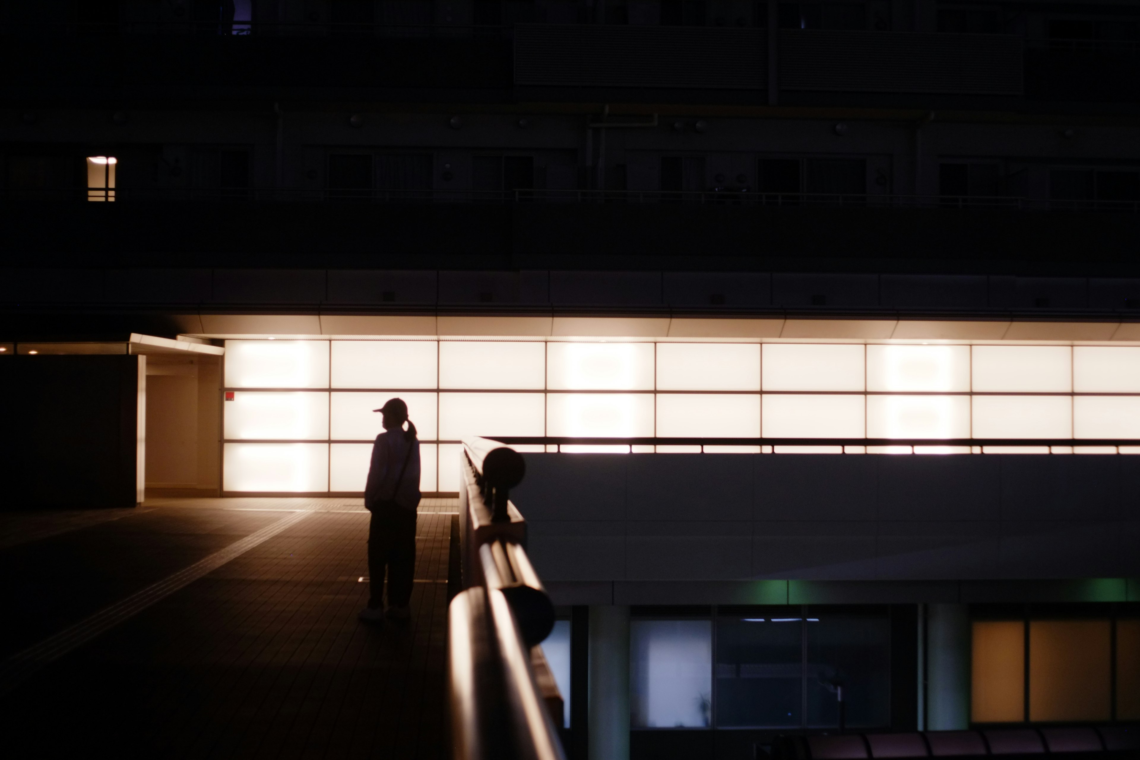 A person standing in front of bright windows in a nighttime urban setting