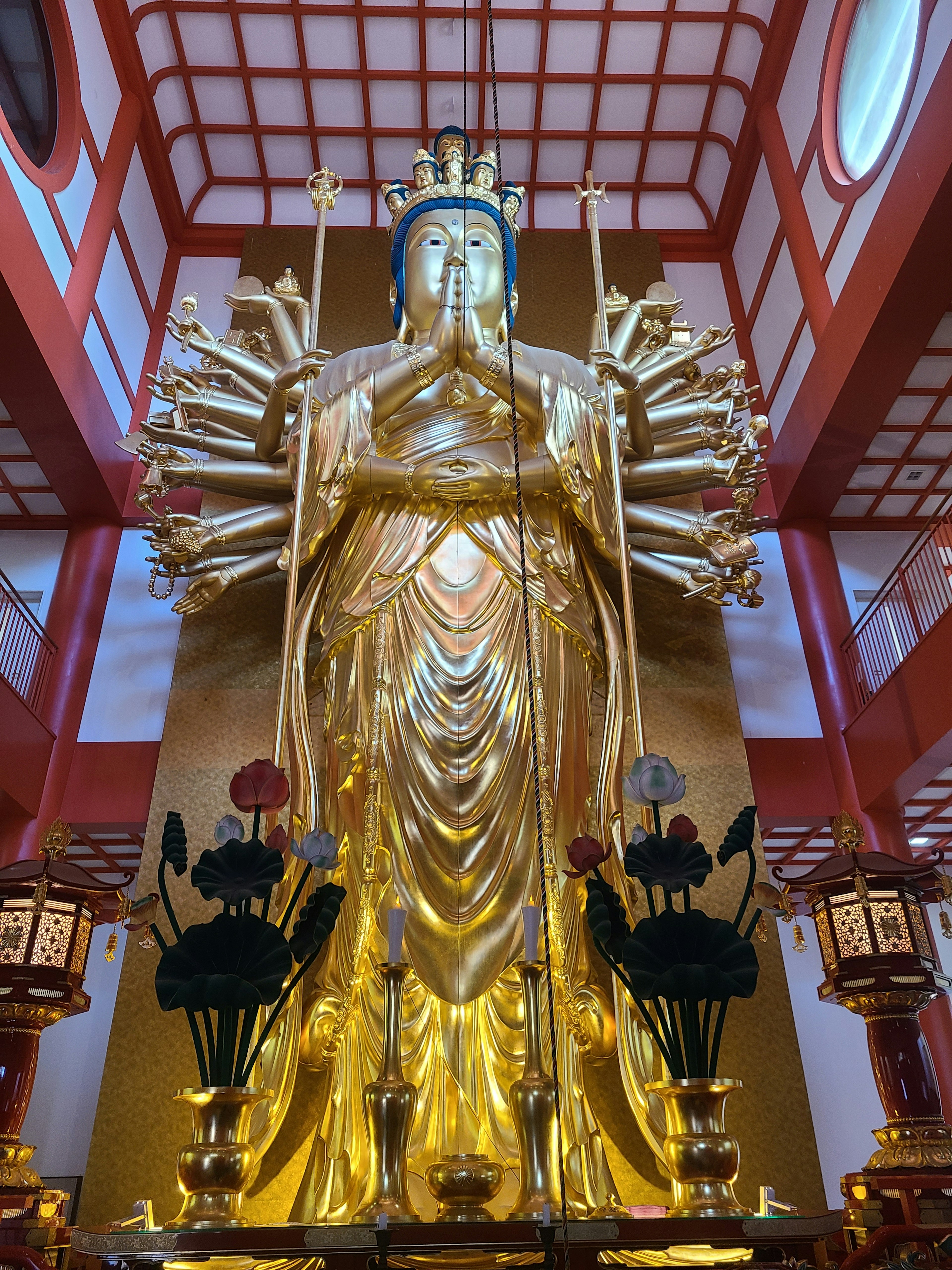 Grande statua dorata di Kannon che si erge in una sala del tempio