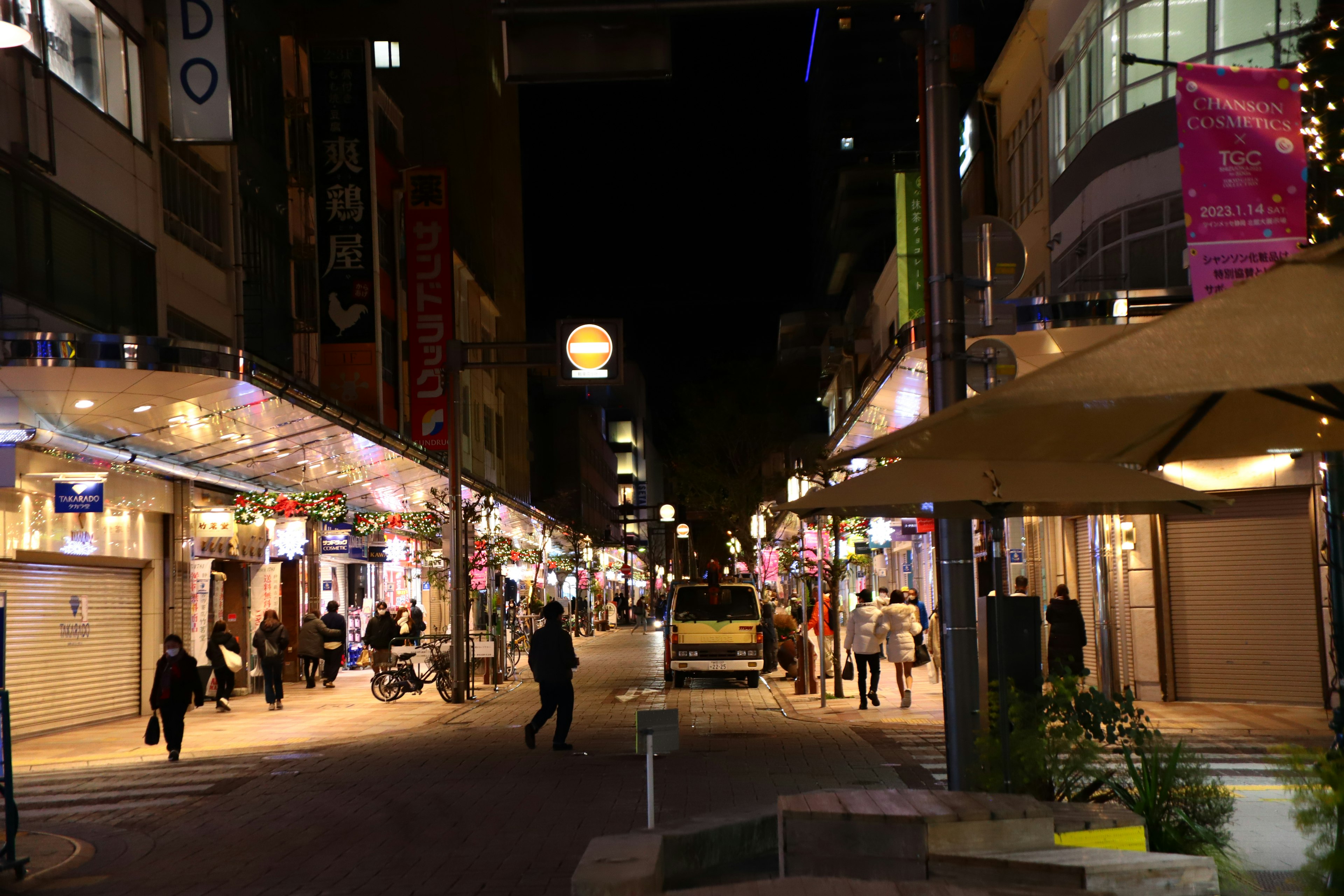 Nighttime street scene with people walking and bright signage