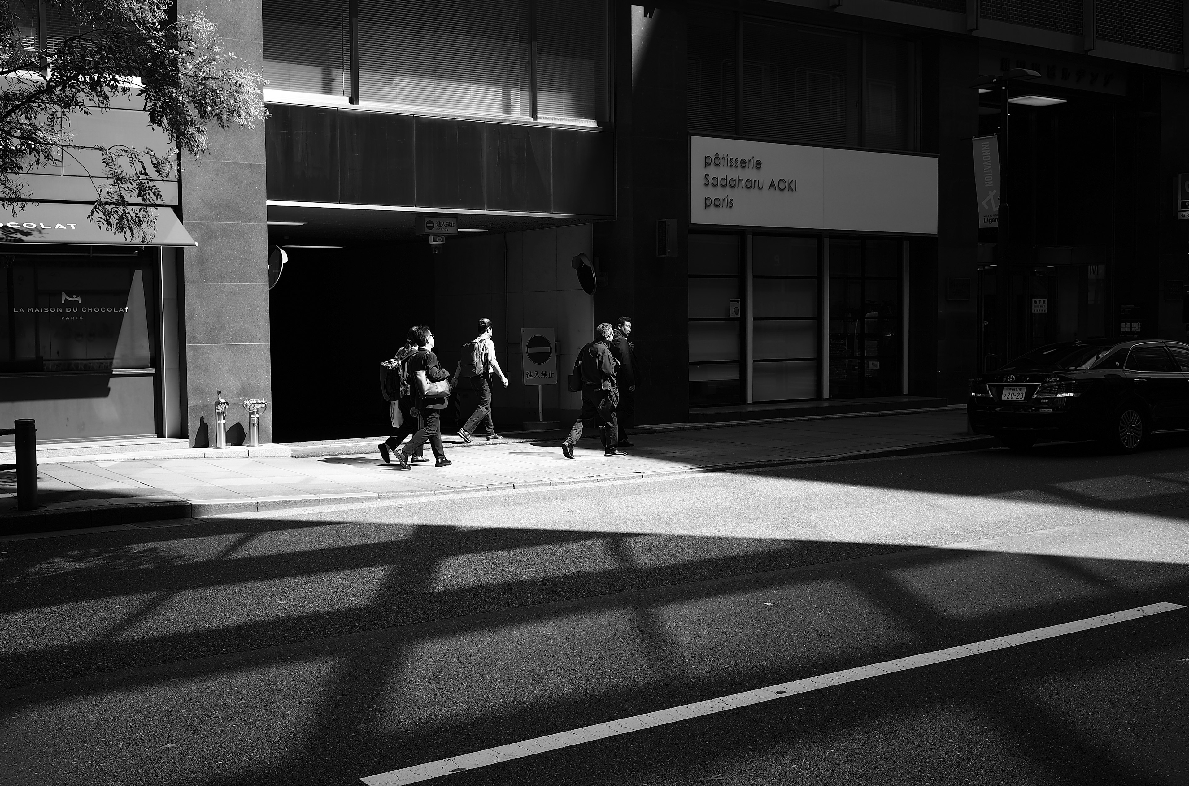 Black and white photo of people crossing a crosswalk in an urban setting