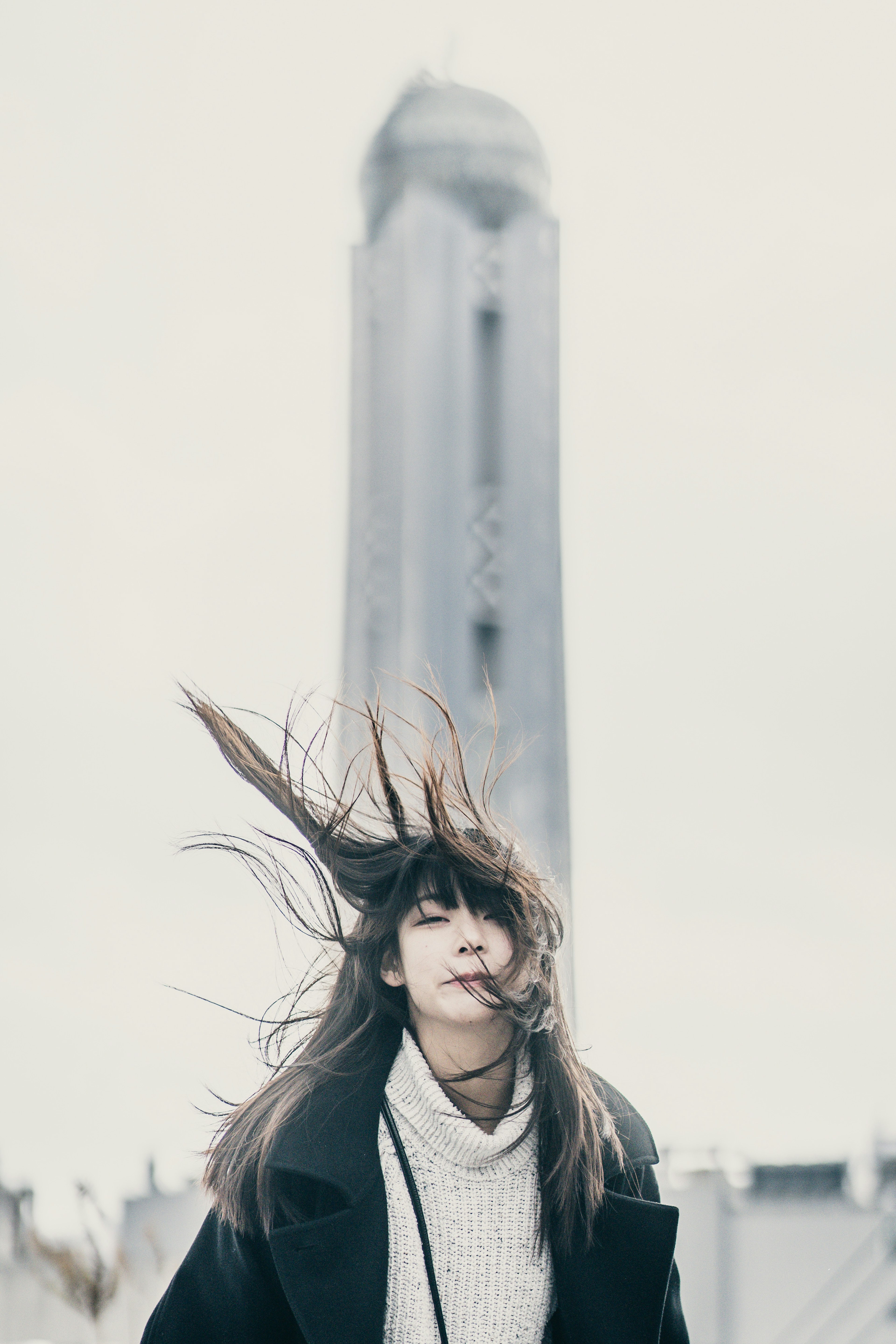 Frau mit wehenden Haaren und hohem Turm im Hintergrund