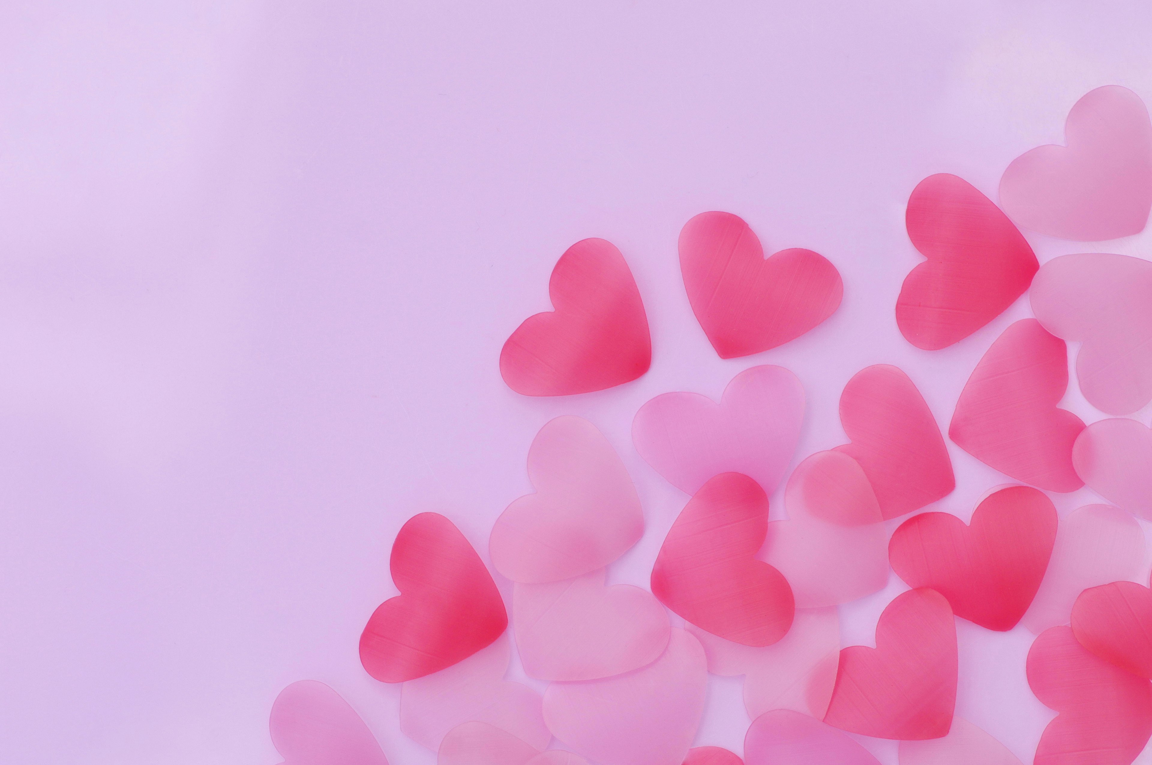 Scattered pink heart-shaped decorations on a pastel background