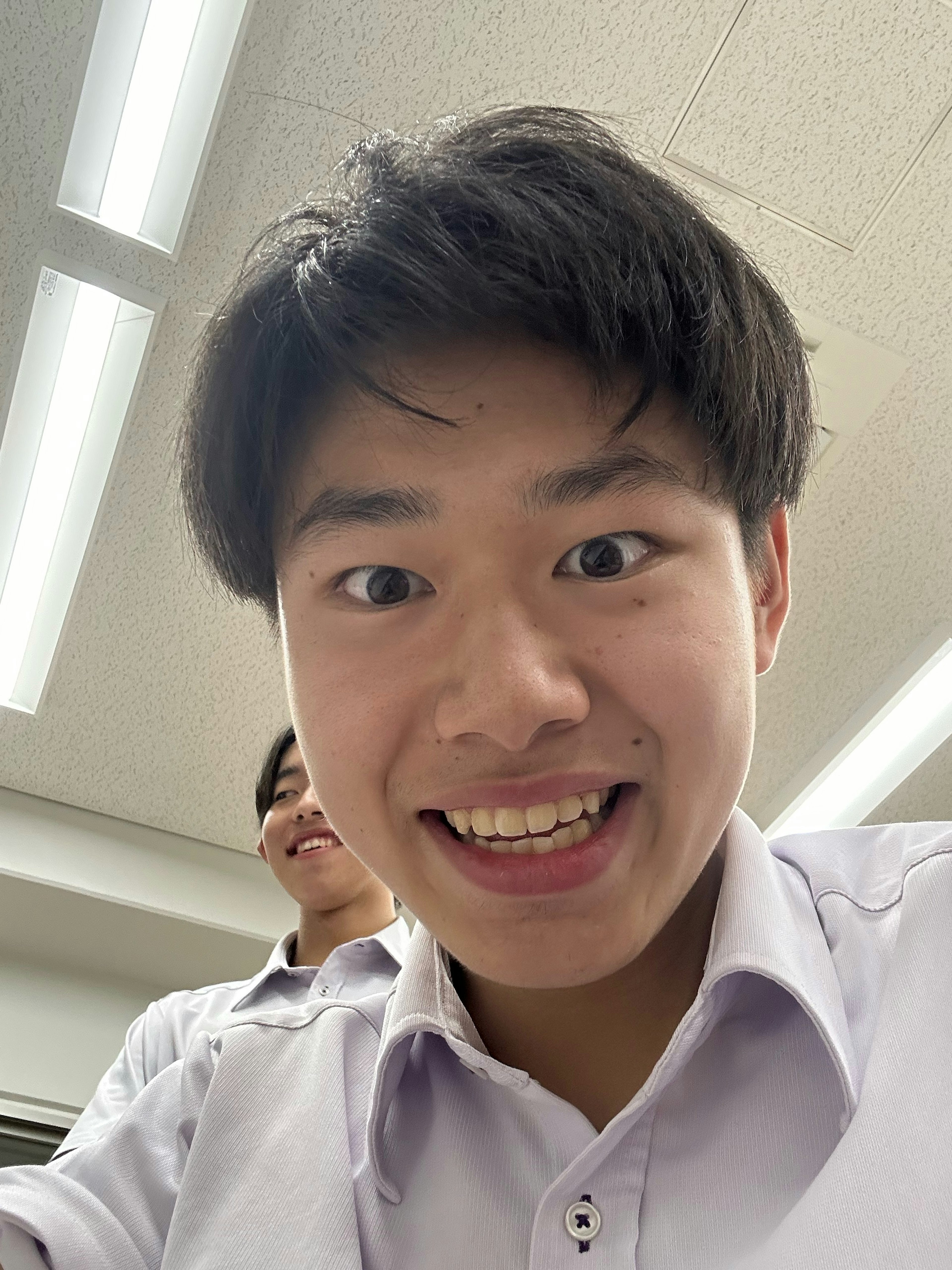 A male student smiling at the camera in a classroom