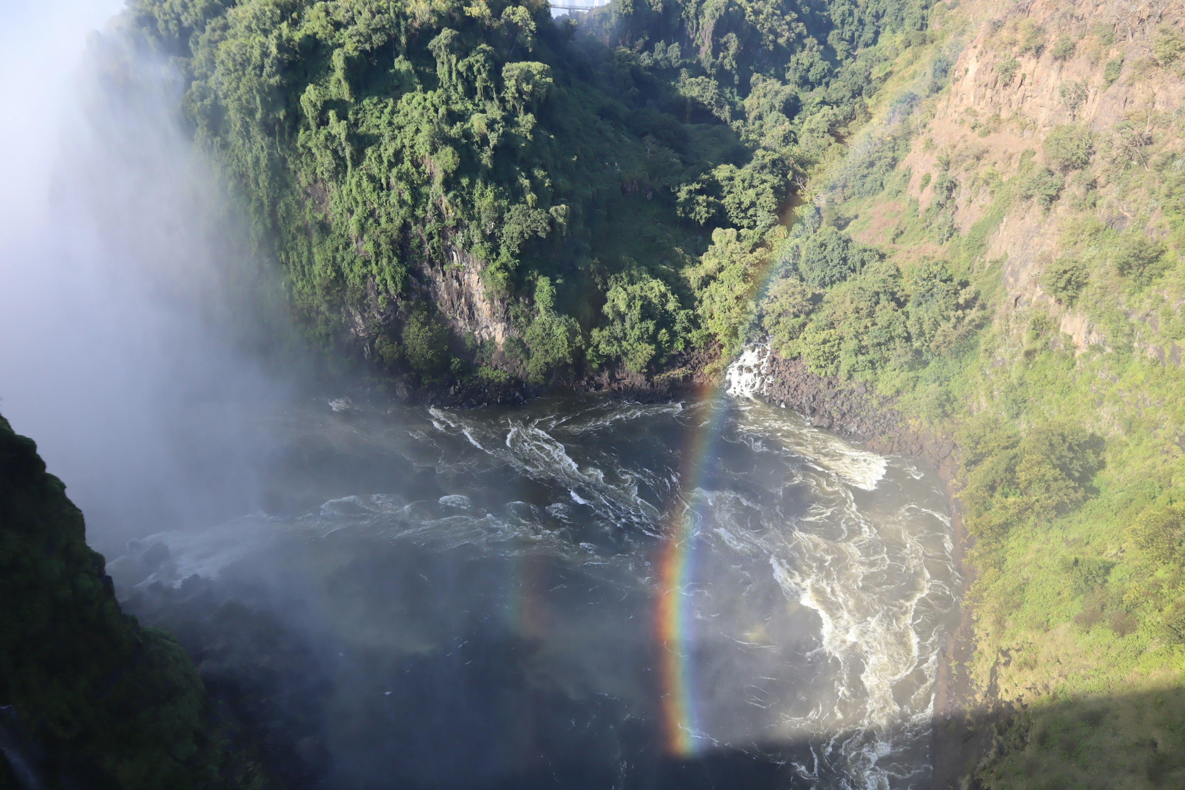 Arco iris sobre un río cerca de acantilados verdes