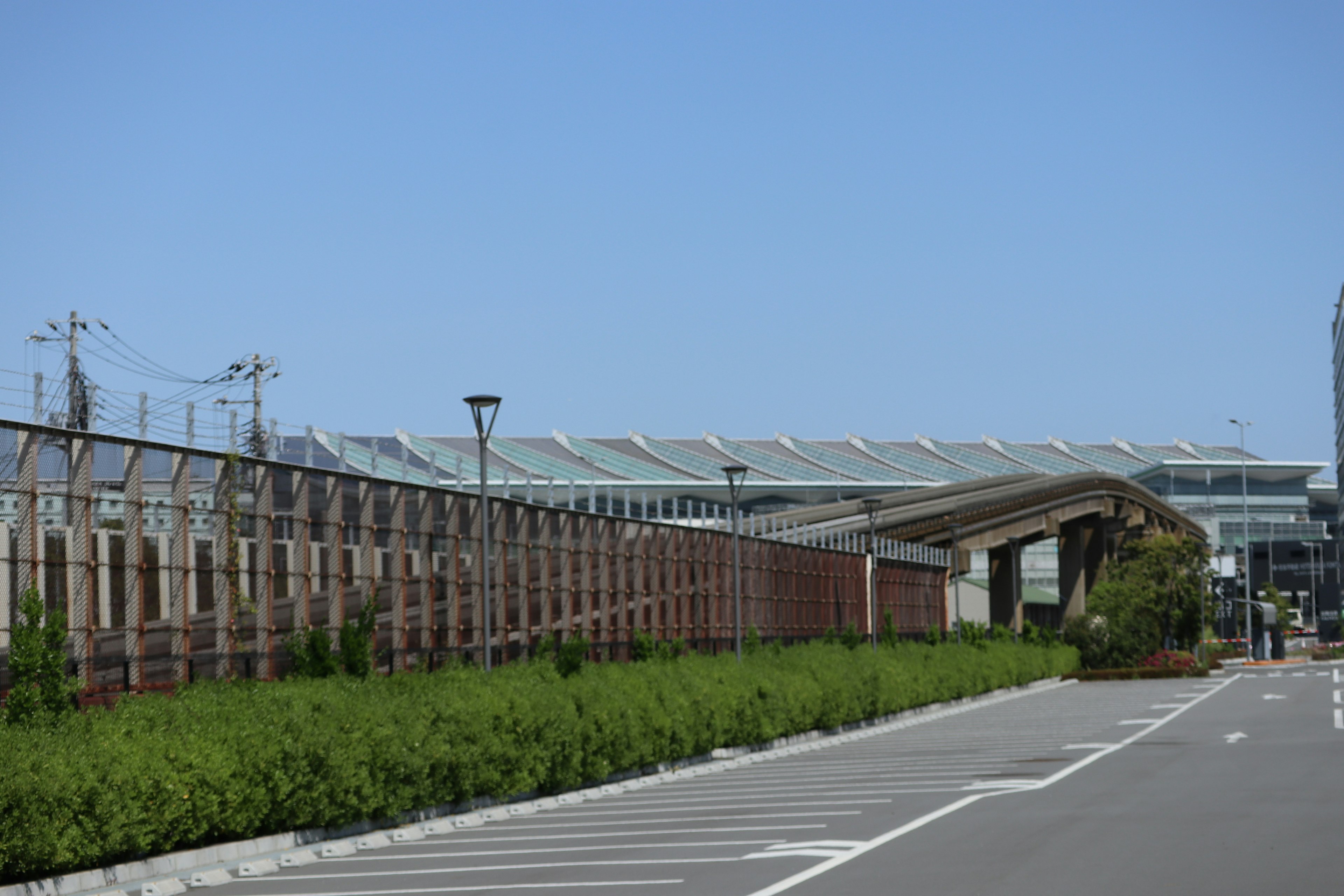 Vista de una estación de tren moderna con un amplio estacionamiento y paisajismo verde