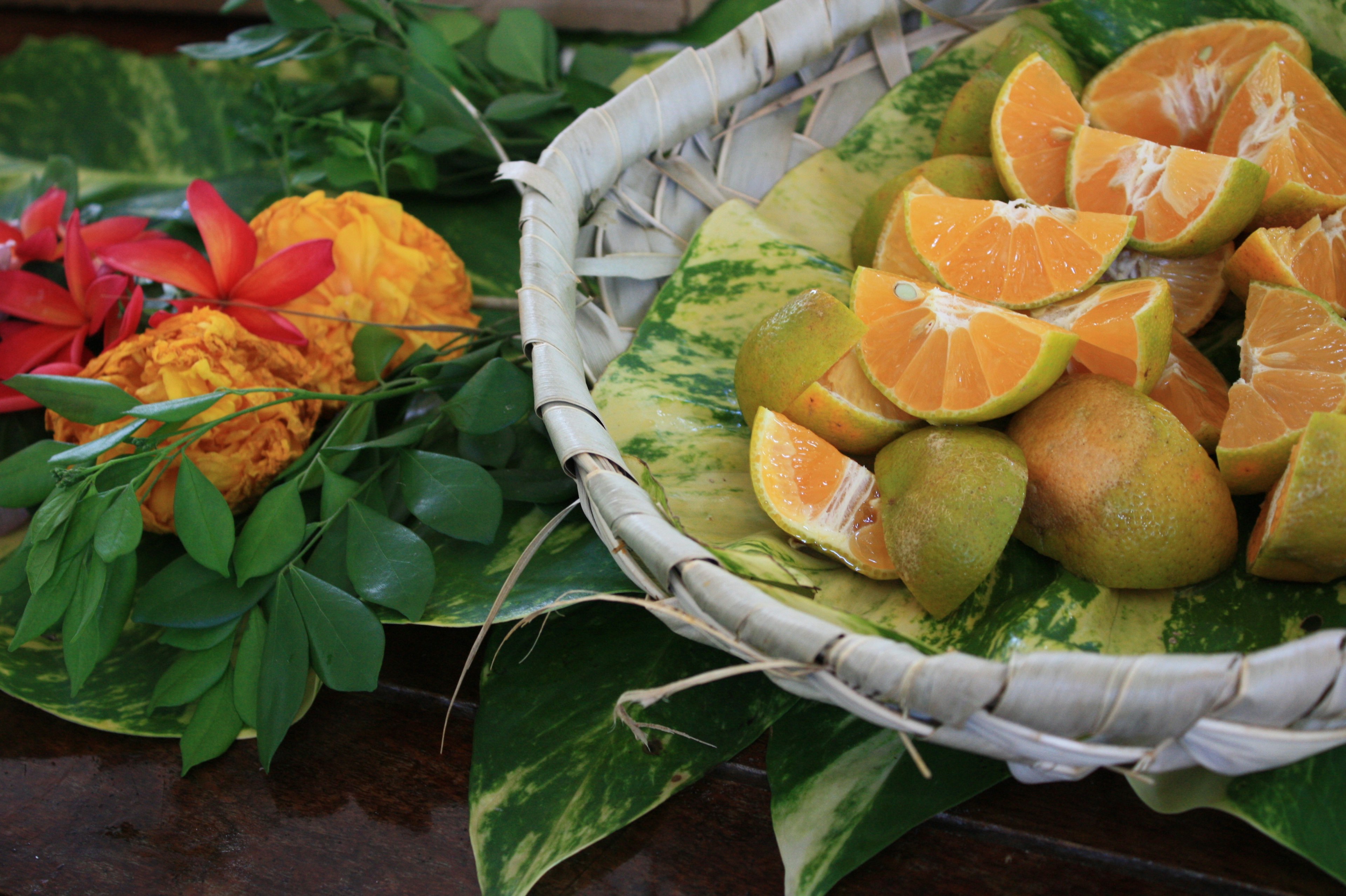 Sebuah keranjang yang penuh dengan buah berwarna-warni dan susunan bunga