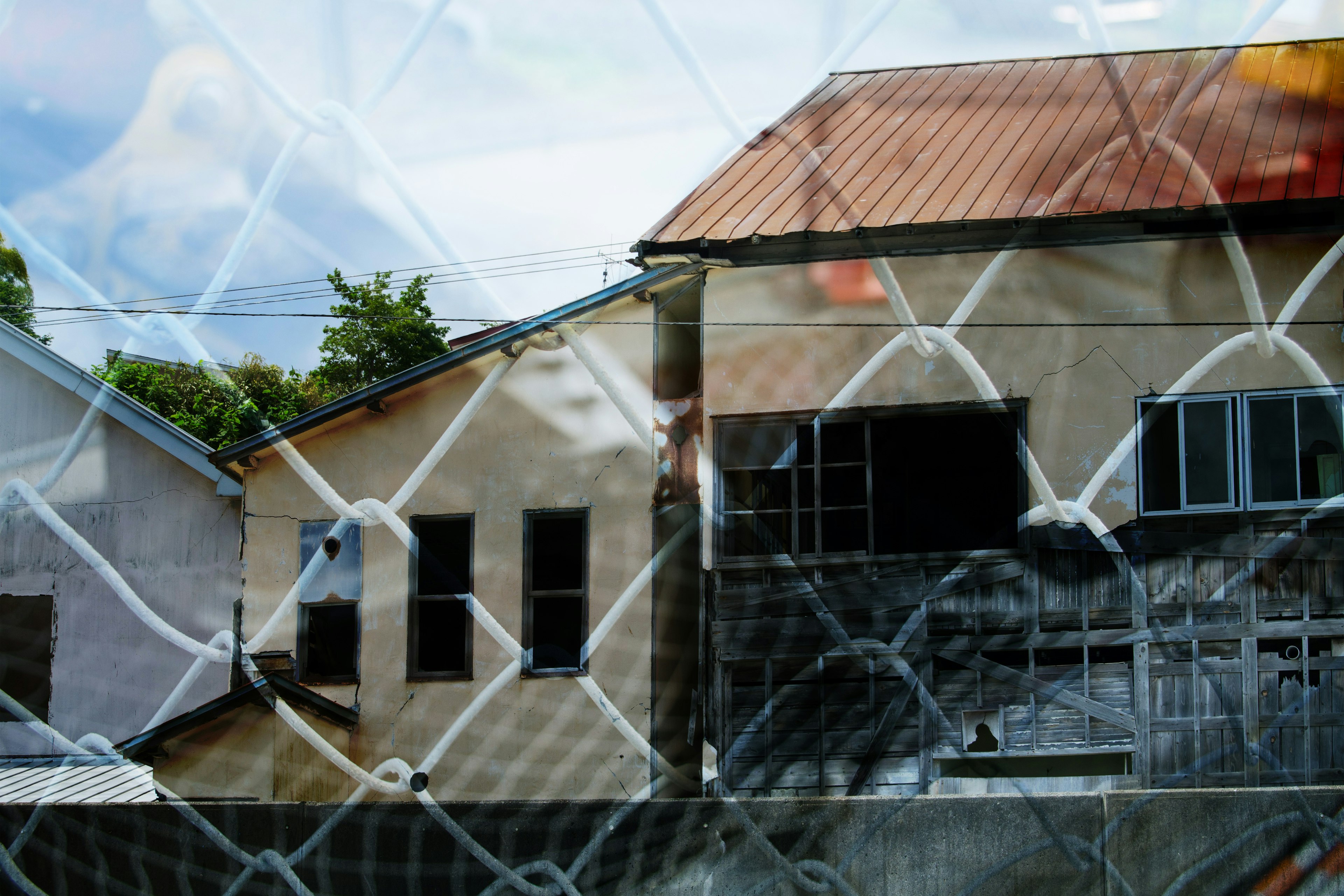 Old buildings viewed through a chain-link fence with blue sky