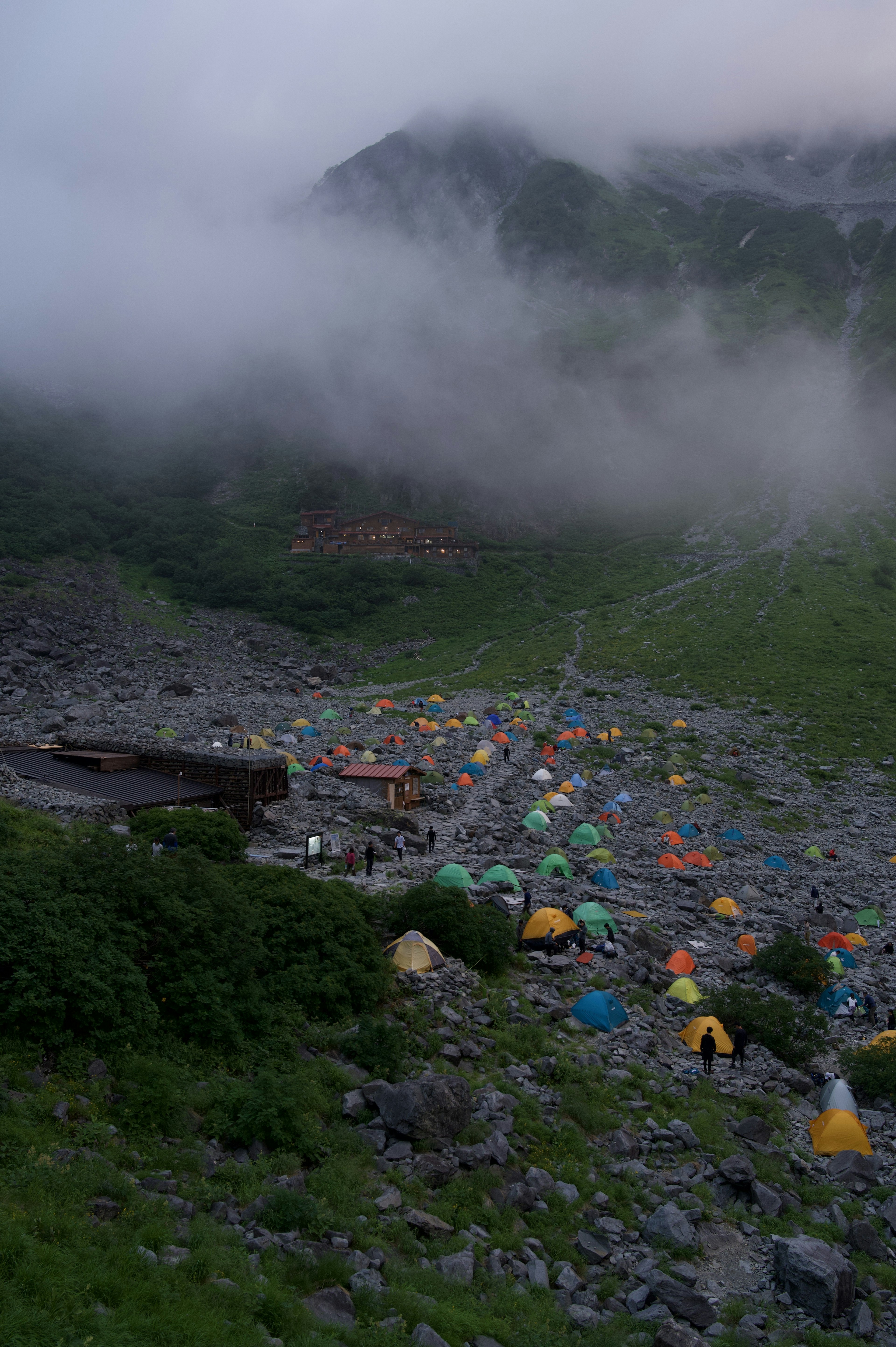 Tendas coloridas dispersas en un campamento de montaña cubierto de niebla