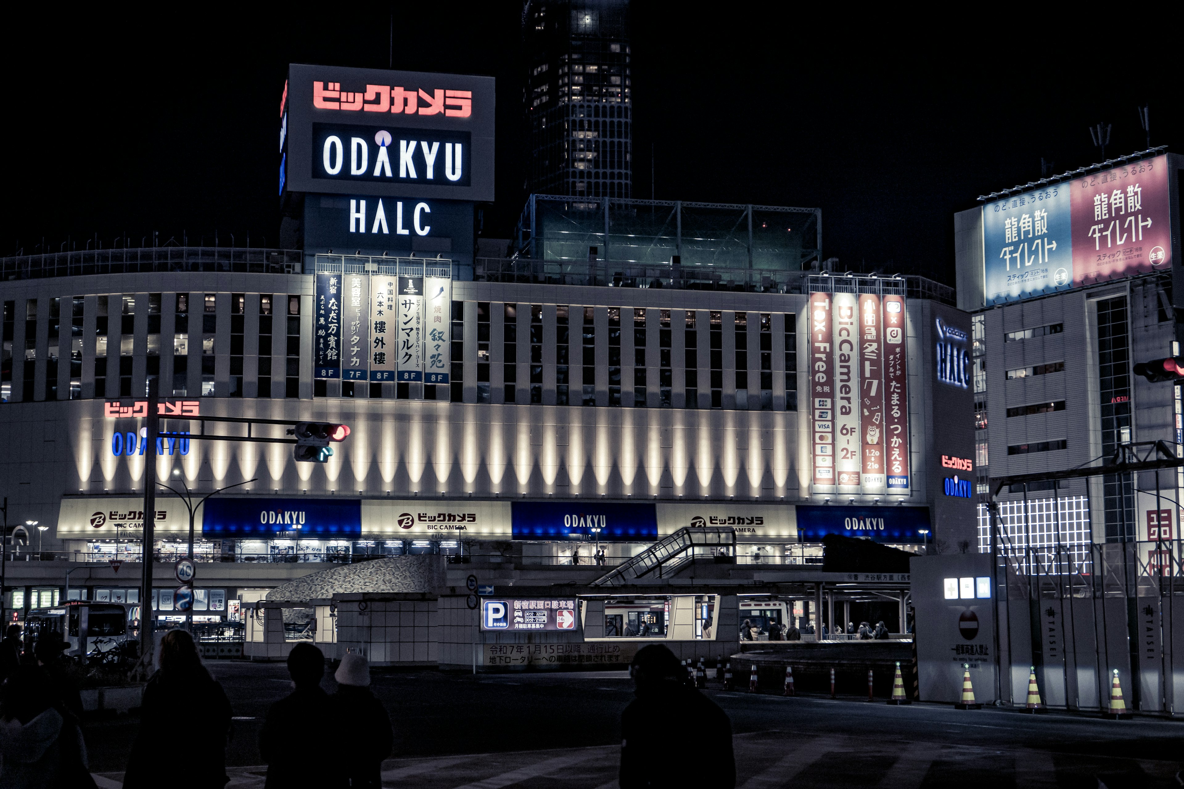 Nachtansicht von Odakyu HALC mit hellen Neonlichtern und umliegenden Gebäuden