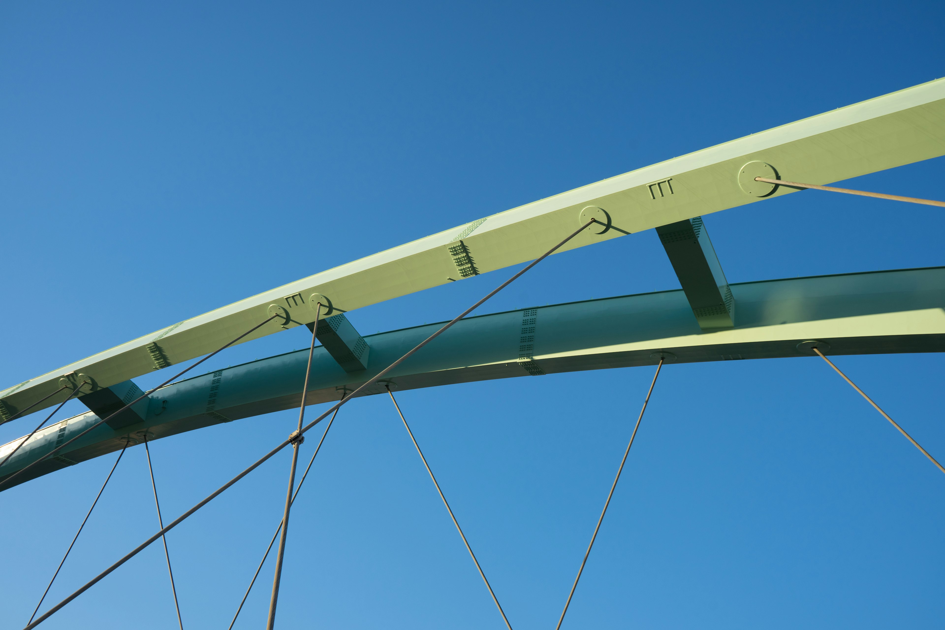 Part of a green bridge arch under a blue sky