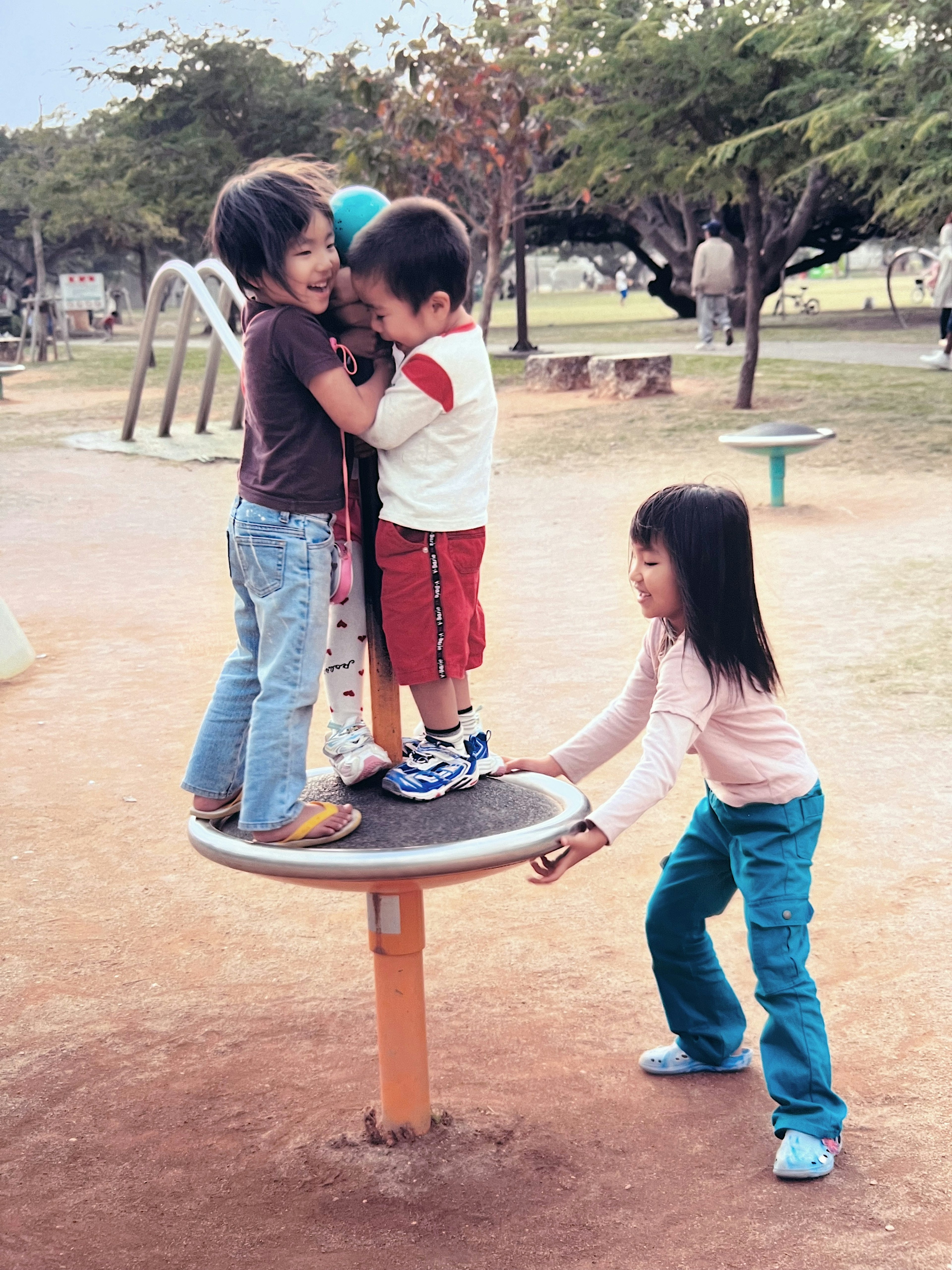 Anak-anak bermain di peralatan taman yang berputar di taman