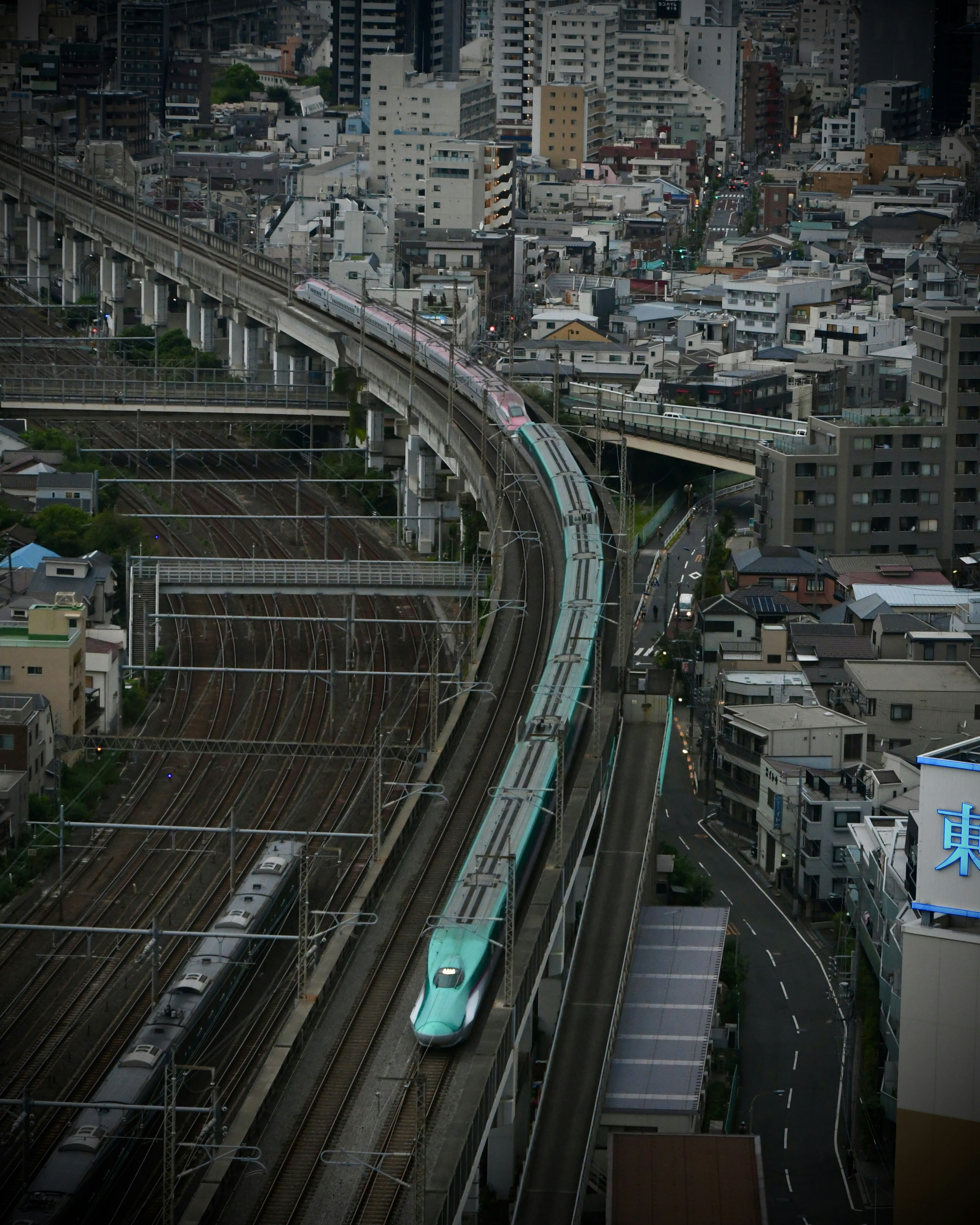 Tàu Shinkansen di chuyển trên đường ray cong với đường chân trời thành phố phía sau