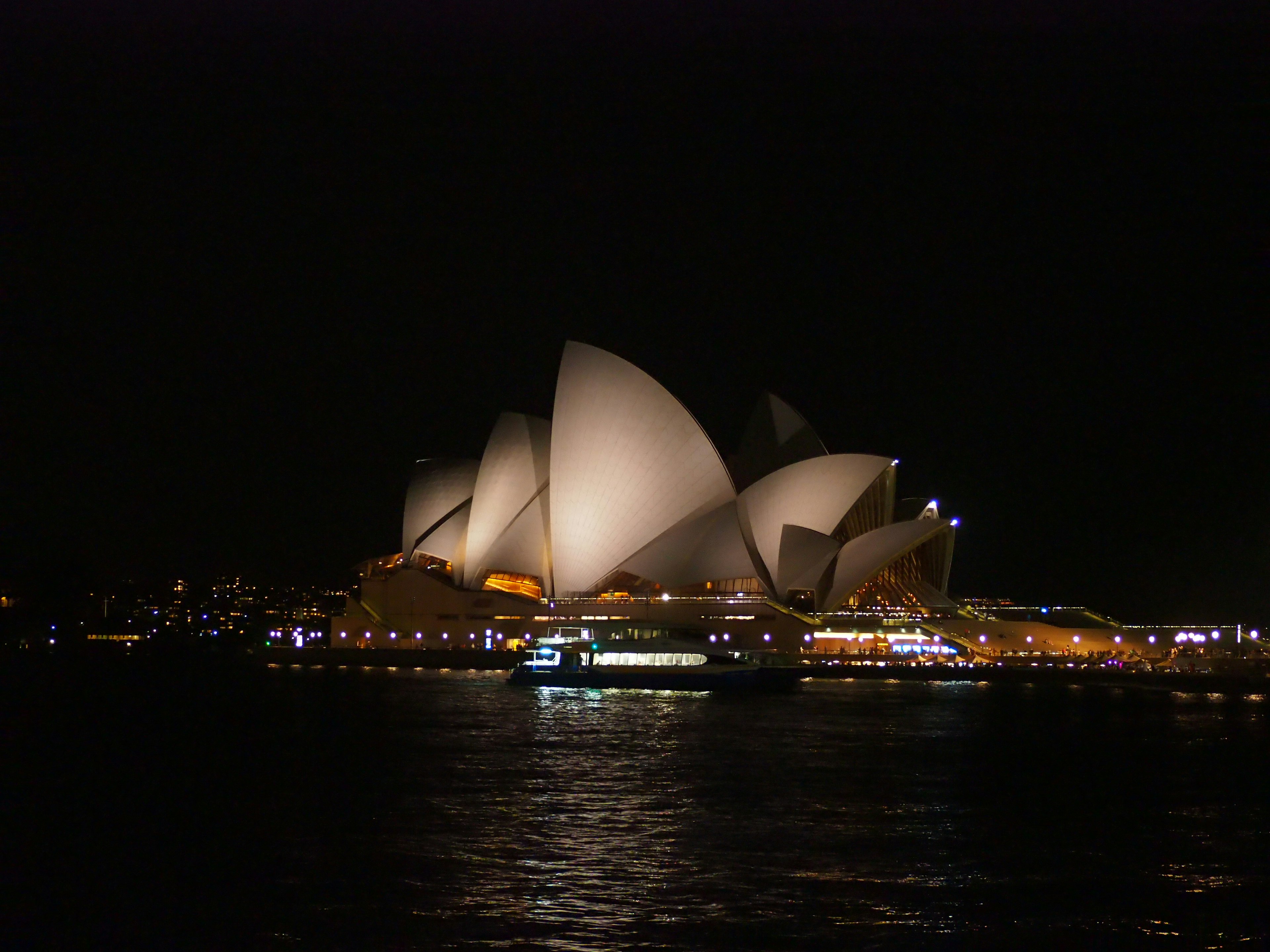 Gedung Opera Sydney di malam hari dengan desain ikonik berbentuk layar yang diterangi di langit gelap