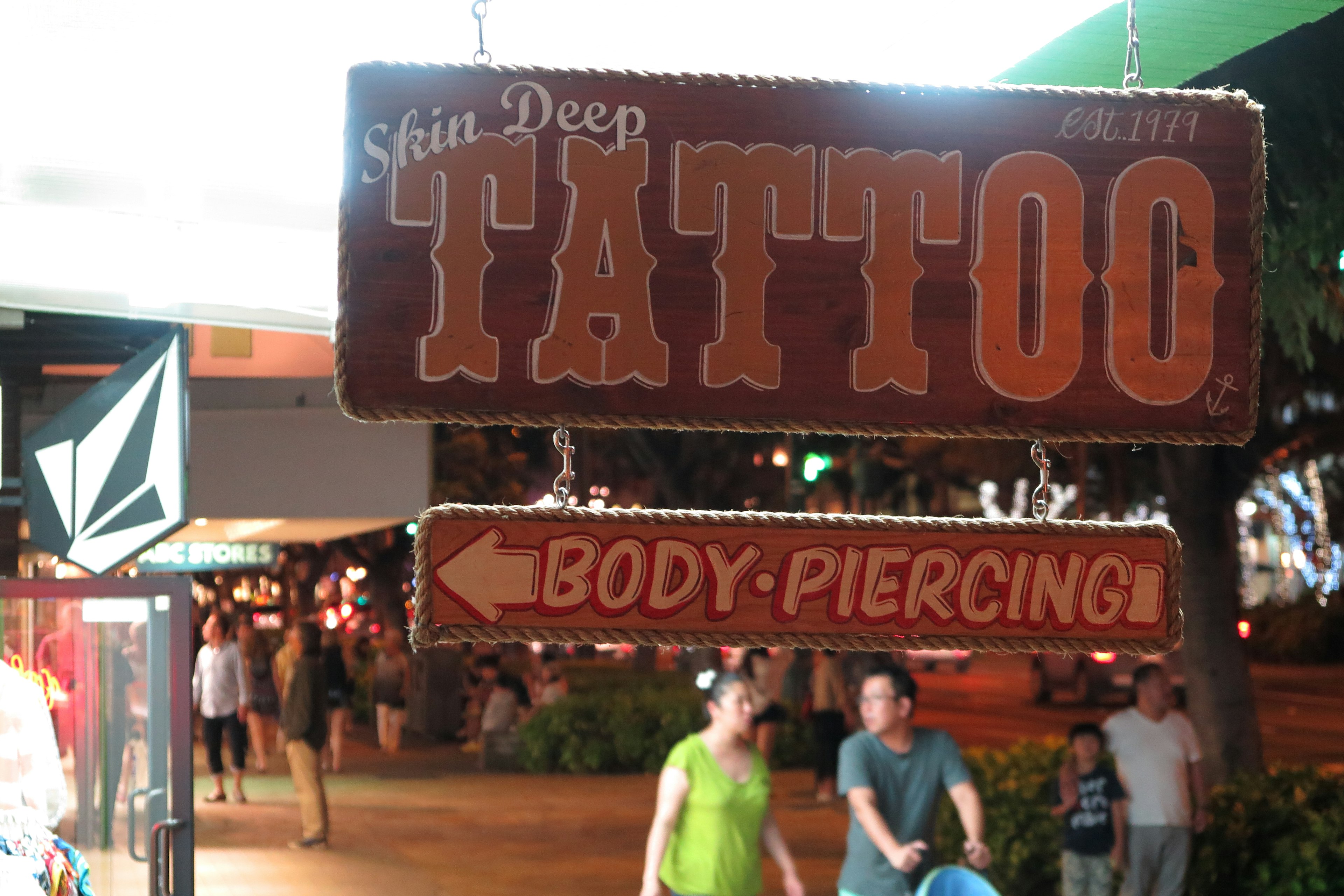 Tattoo- und Piercing-Schild in einer nächtlichen Straße