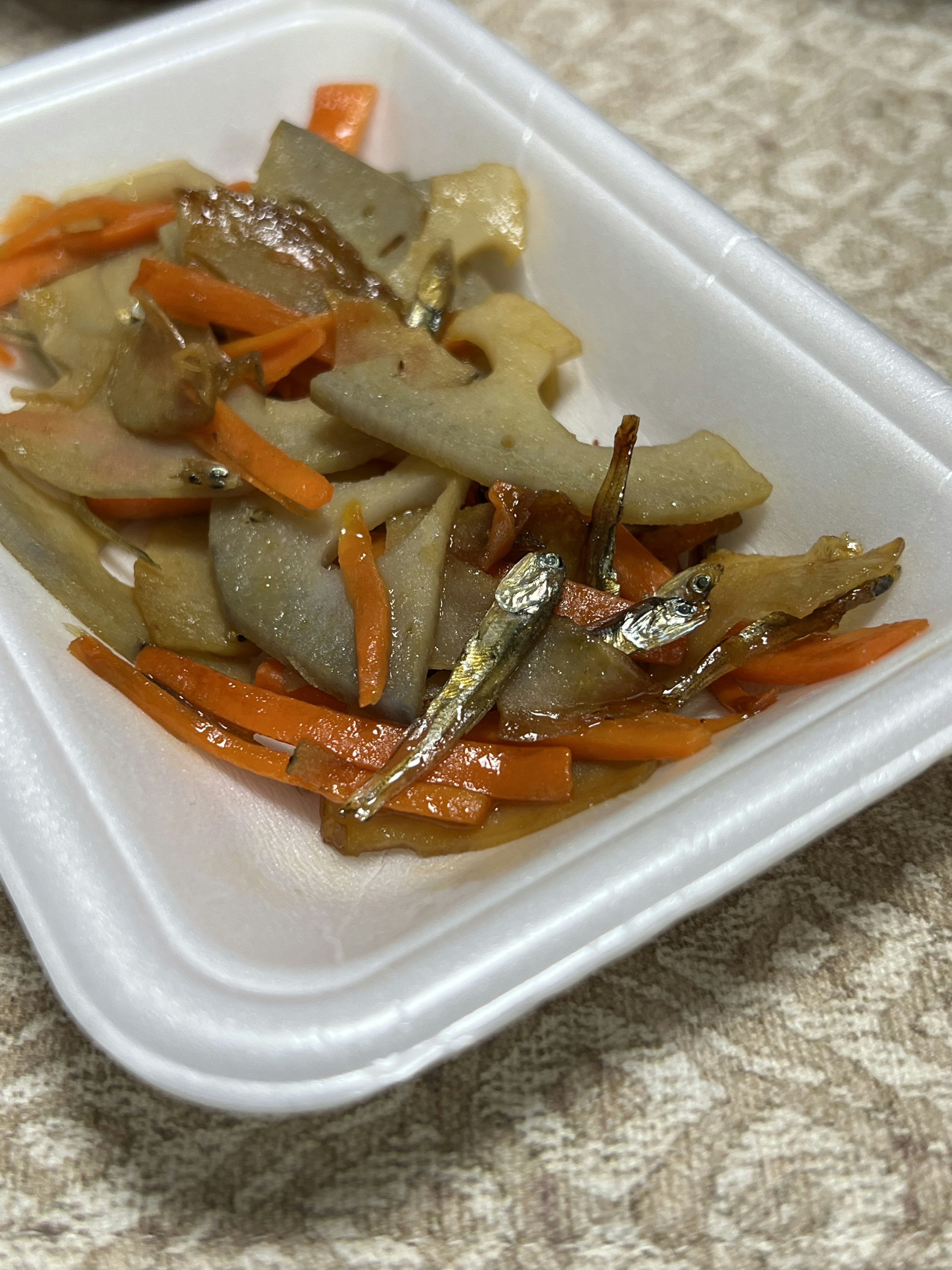 Verduras salteadas y pequeños peces servidos en un recipiente blanco