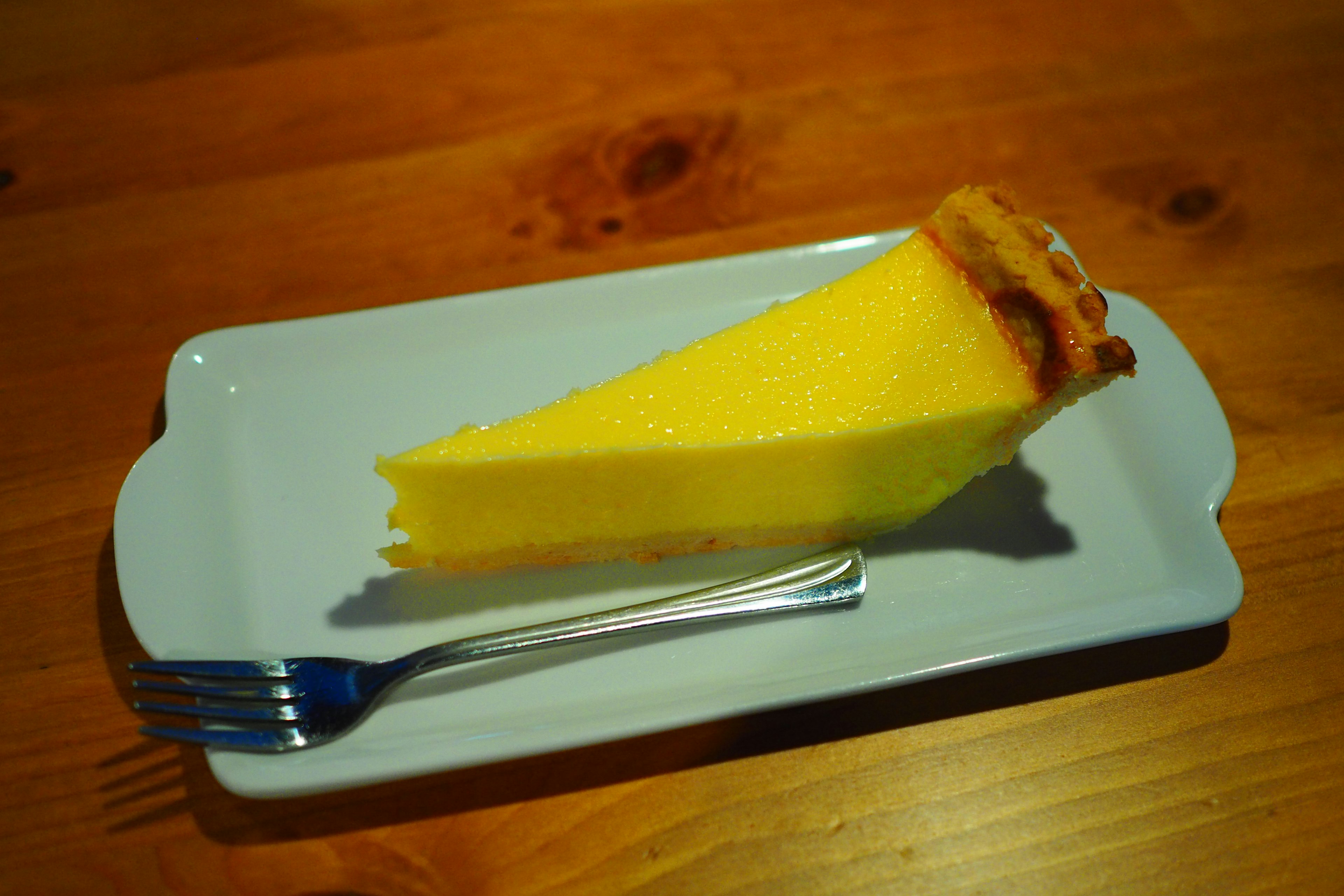 A slice of yellow cake on a white plate with a fork