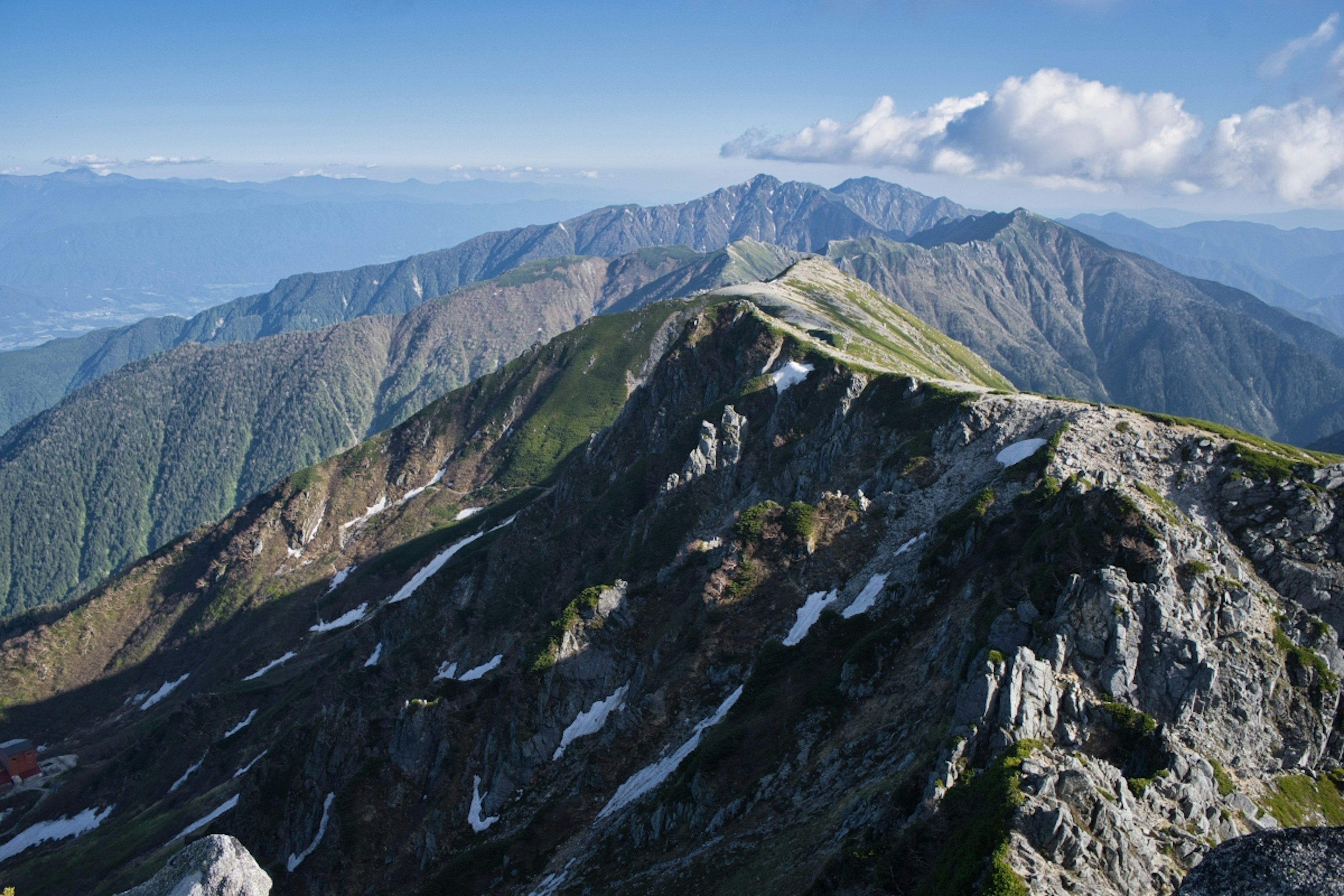 Stunning landscape from mountain peak featuring green hills and blue sky