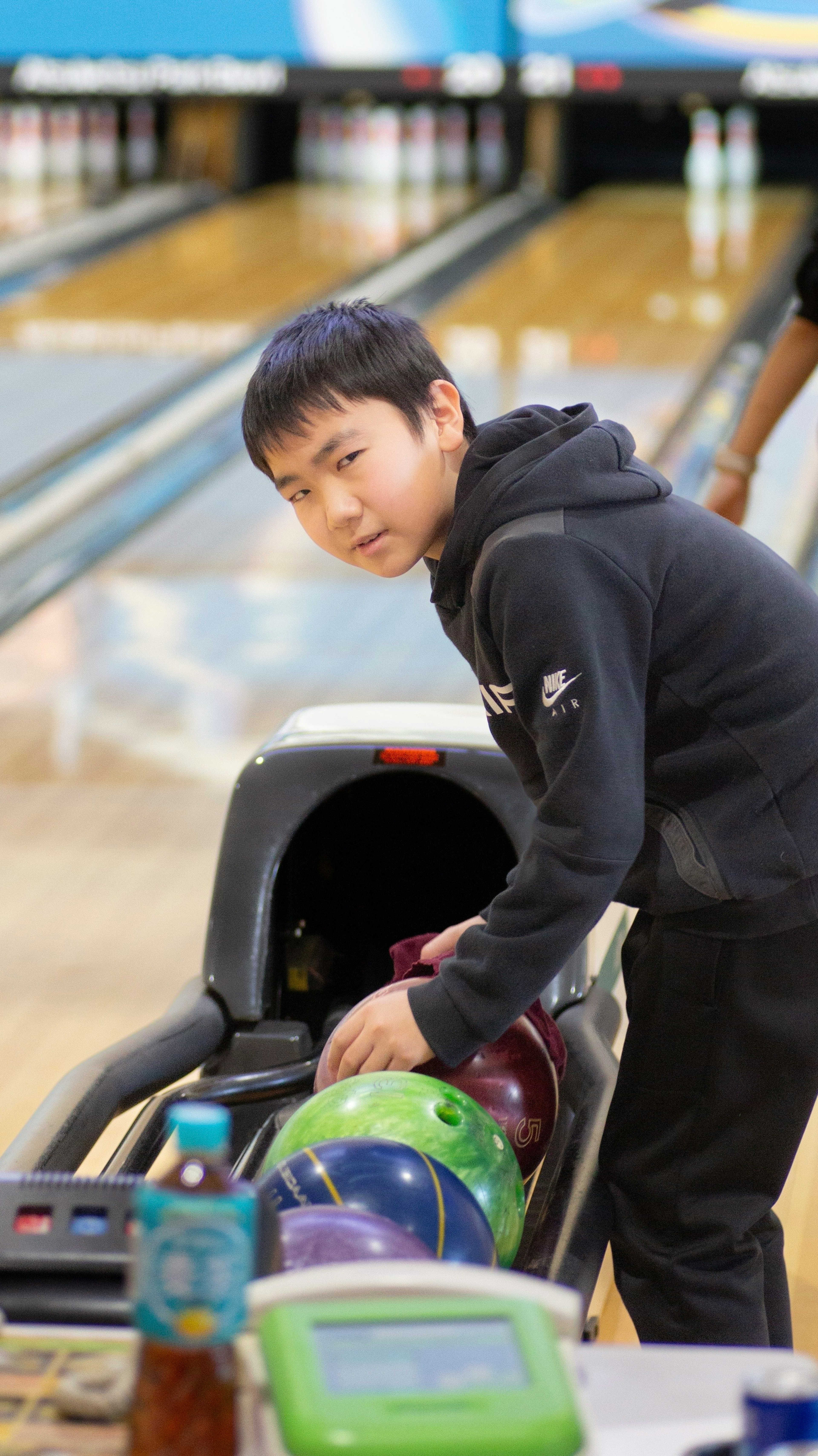 Young boy holding a bowling ball at a bowling alley