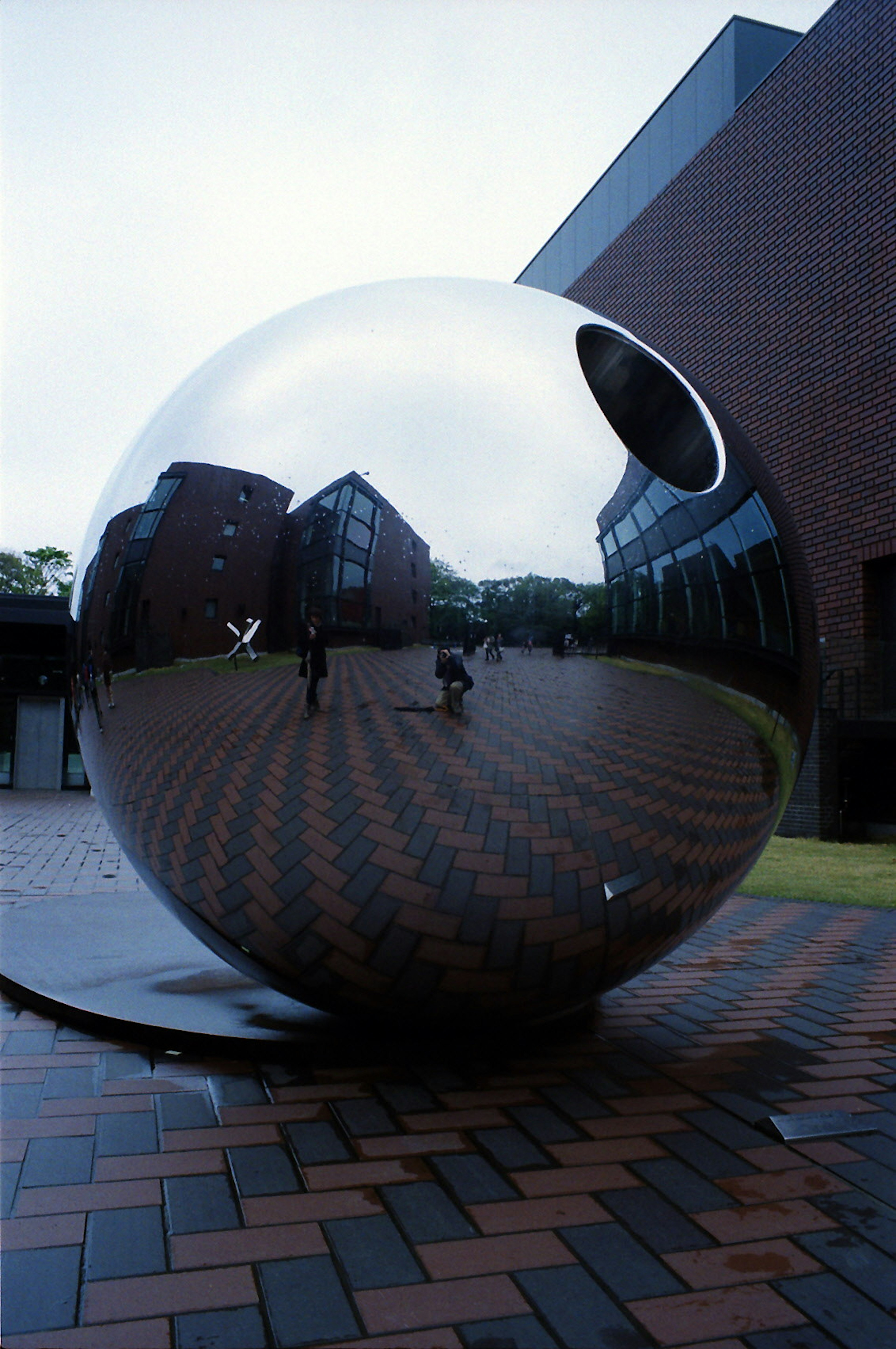 Large reflective sphere in a plaza reflecting surrounding buildings