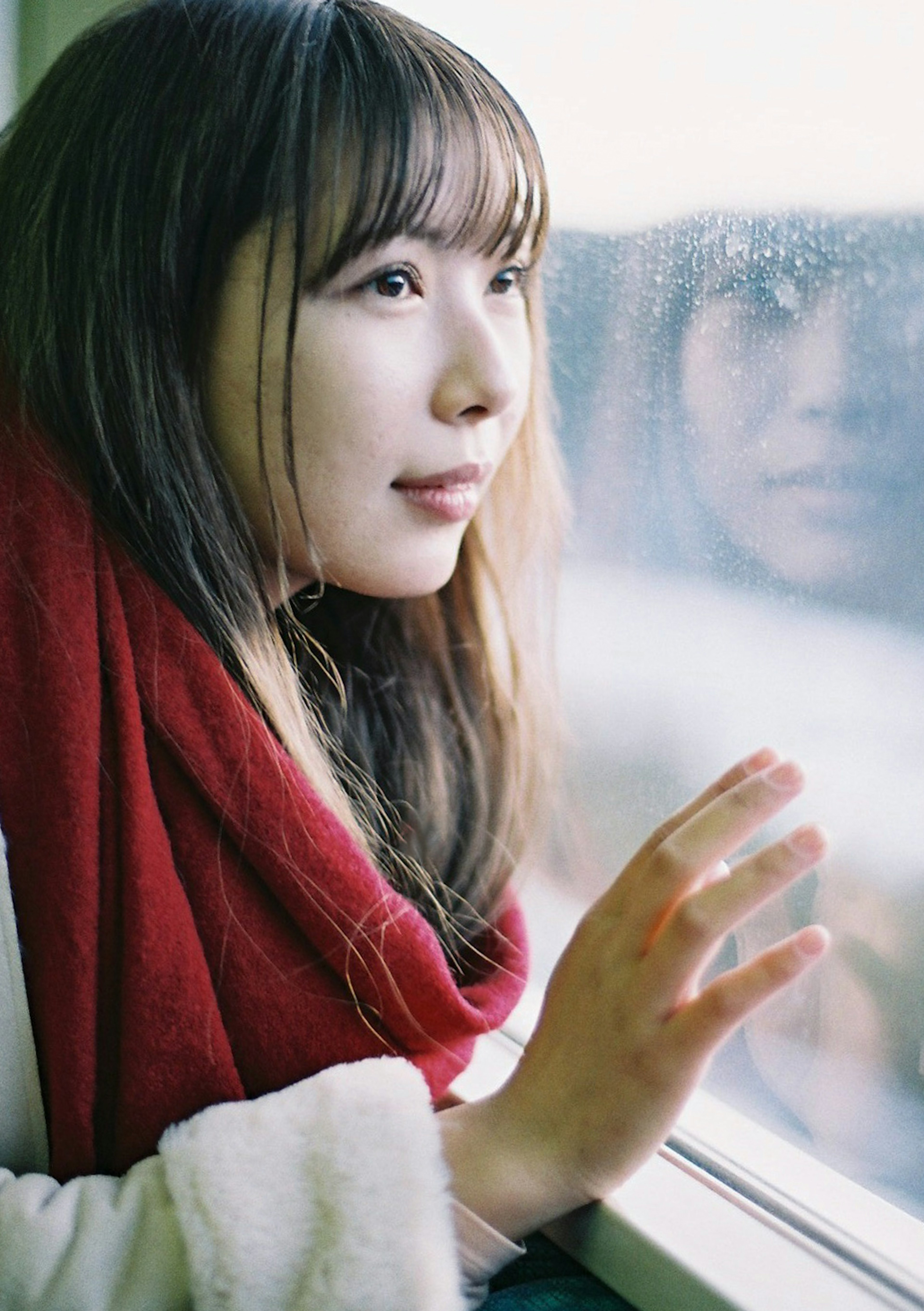 Portrait of a woman gazing out the window wearing a red scarf with soft hair