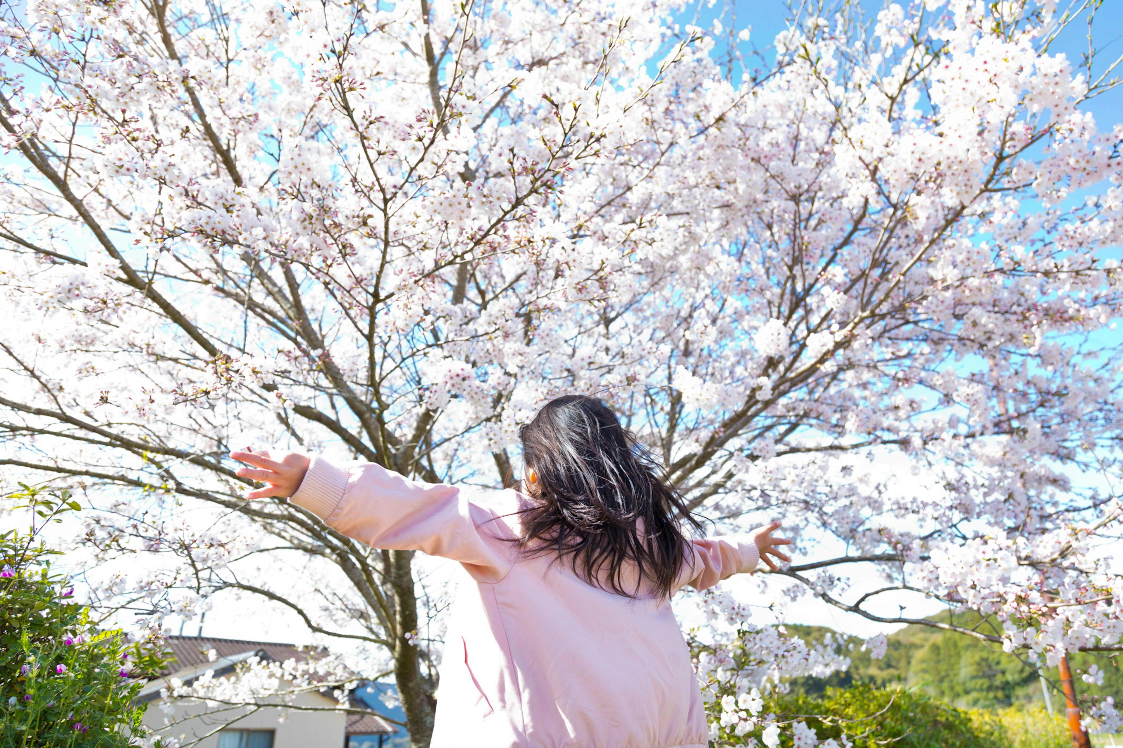 Fille joyeusement debout sous un cerisier en fleurs