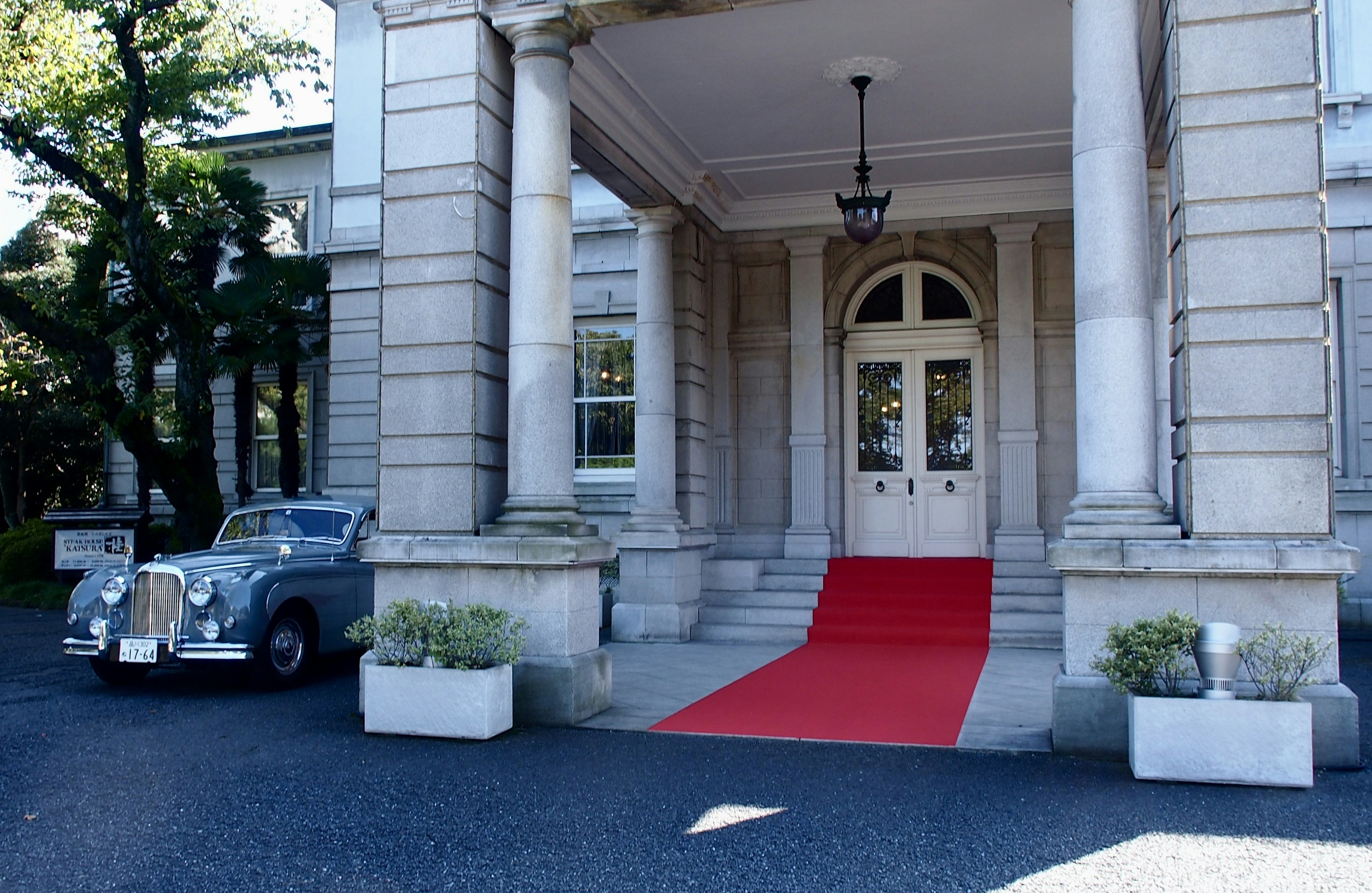 Entrée d'un bâtiment luxueux avec tapis rouge et voiture classique