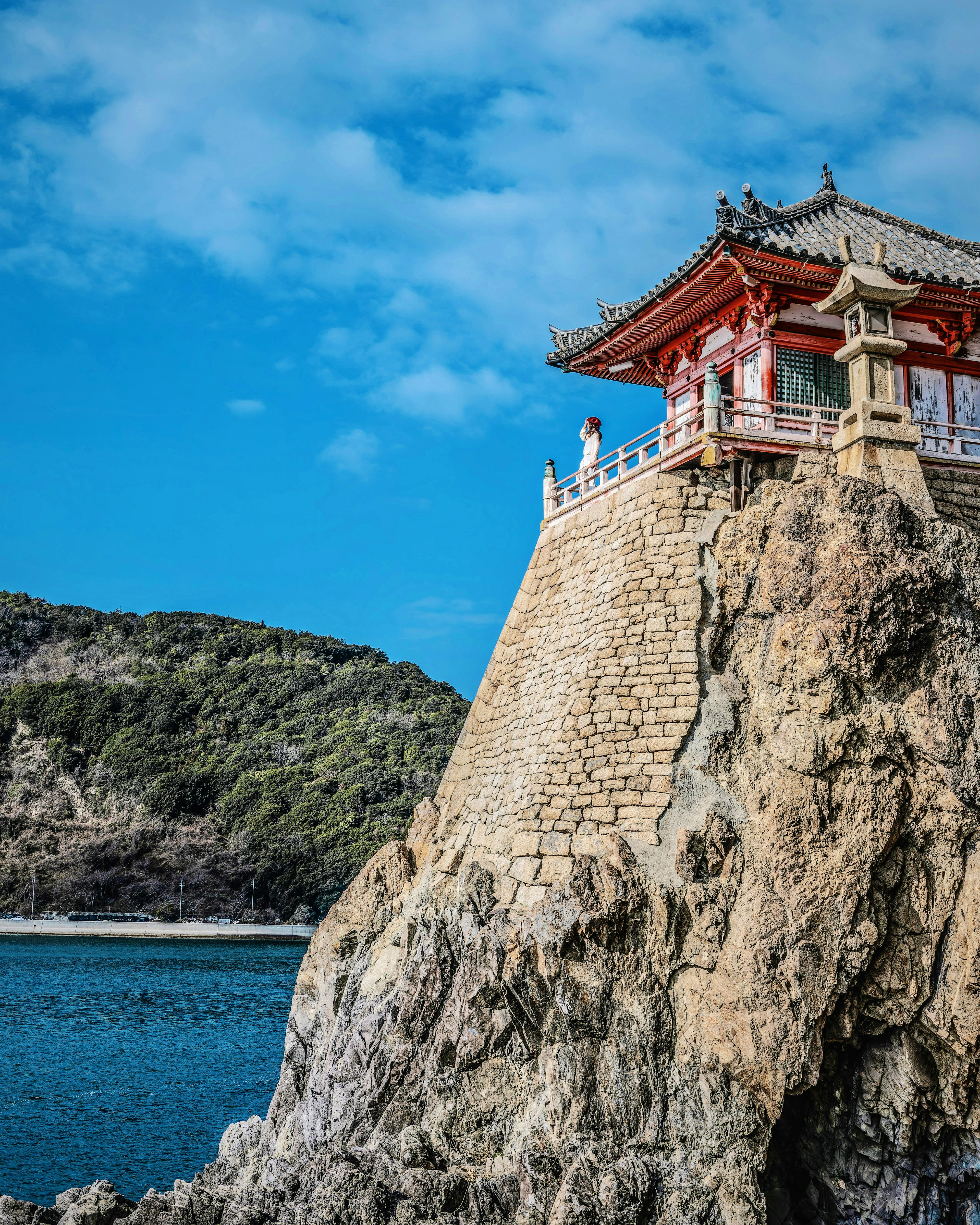 Traditionelles Gebäude auf einer Felsklippe unter einem blauen Himmel mit Blick auf das Meer