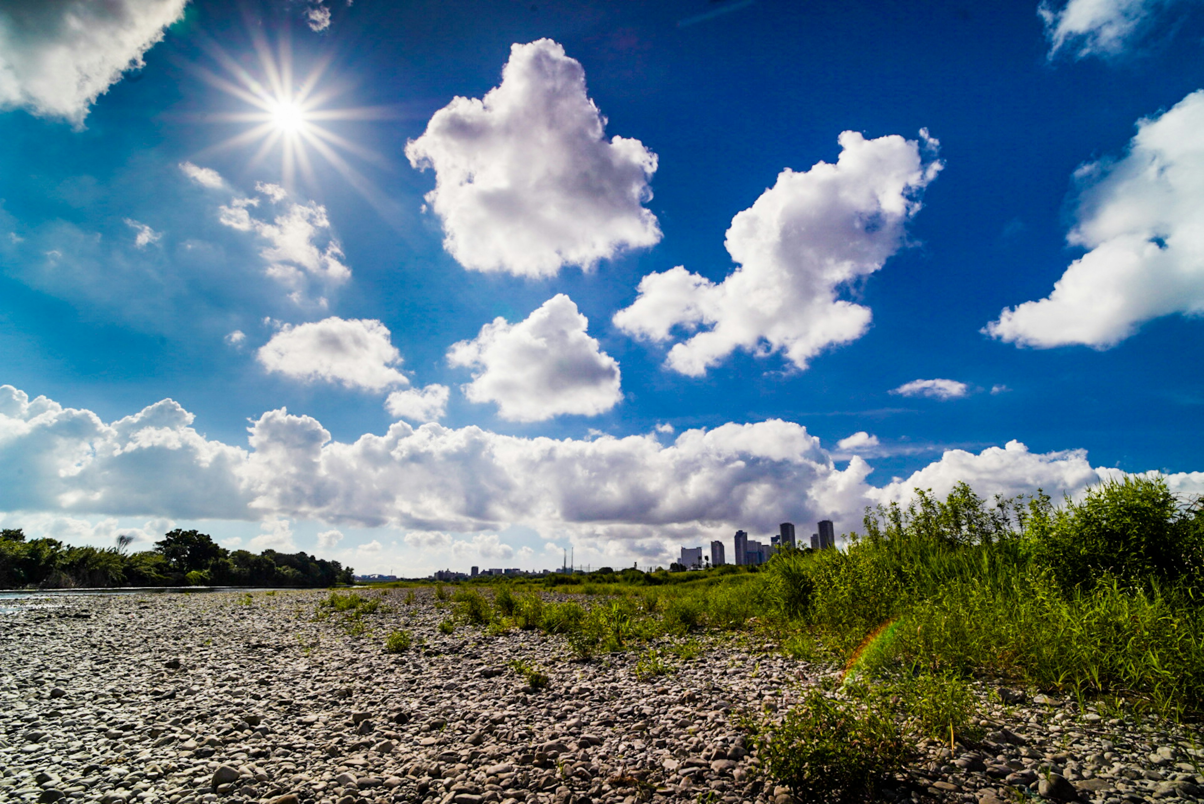 A beautiful landscape with a blue sky, fluffy white clouds, and sunlight shining down