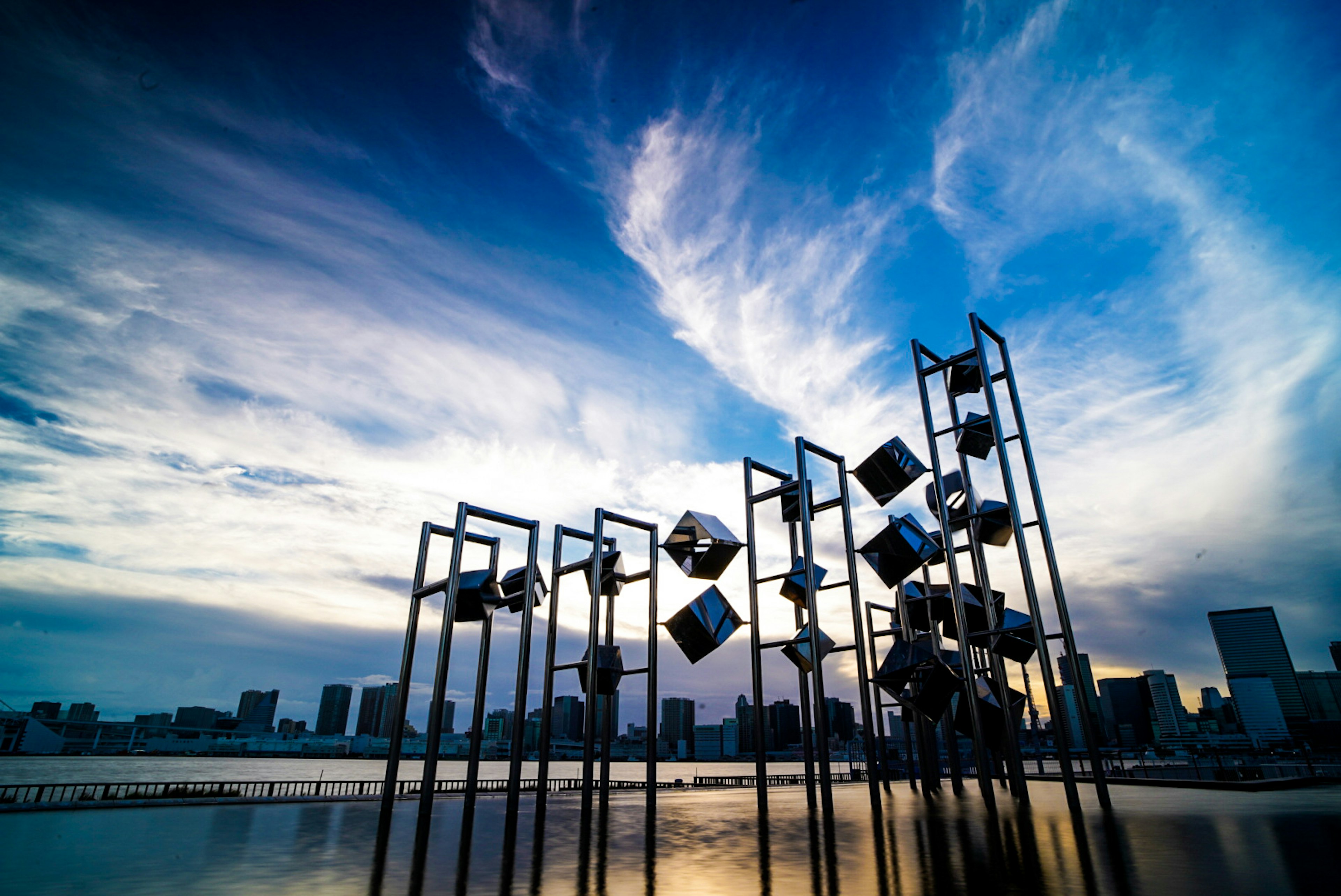 Grupo de esculturas modernas contra un cielo azul y nubes