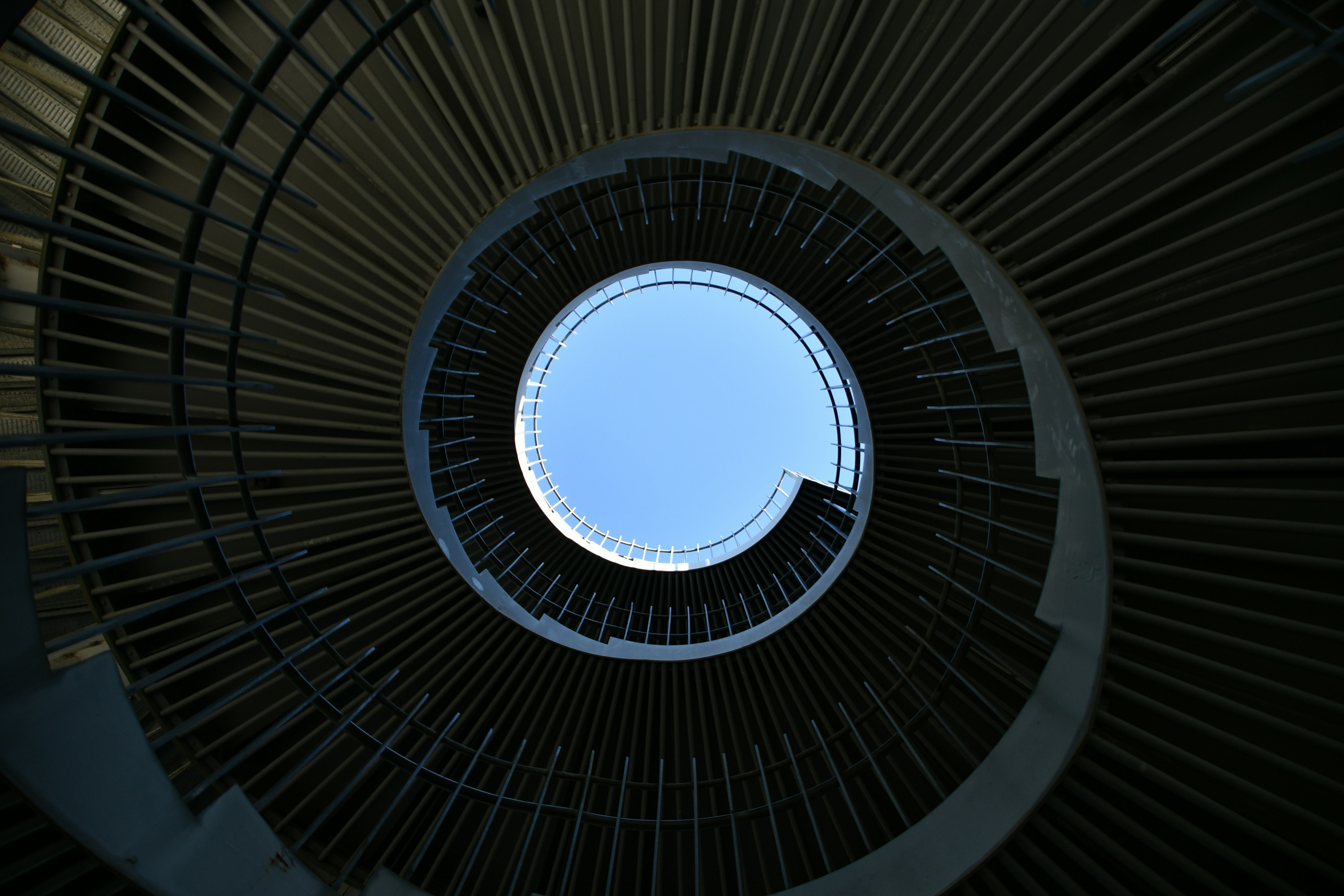 Interior view of a spiral staircase with a blue sky above