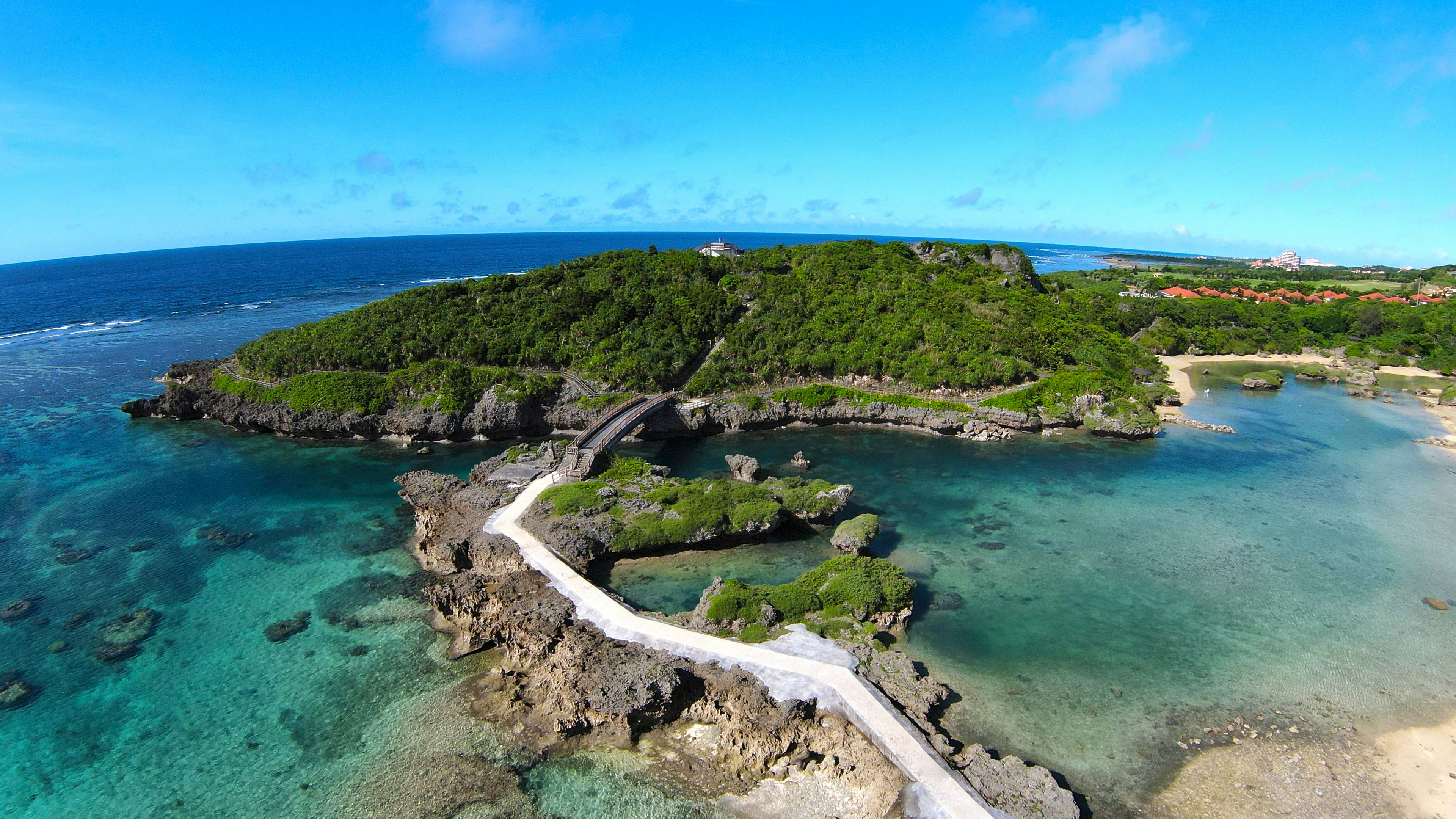 Vue aérienne d'une île verte avec un chemin blanc sinueux entouré d'eau bleue