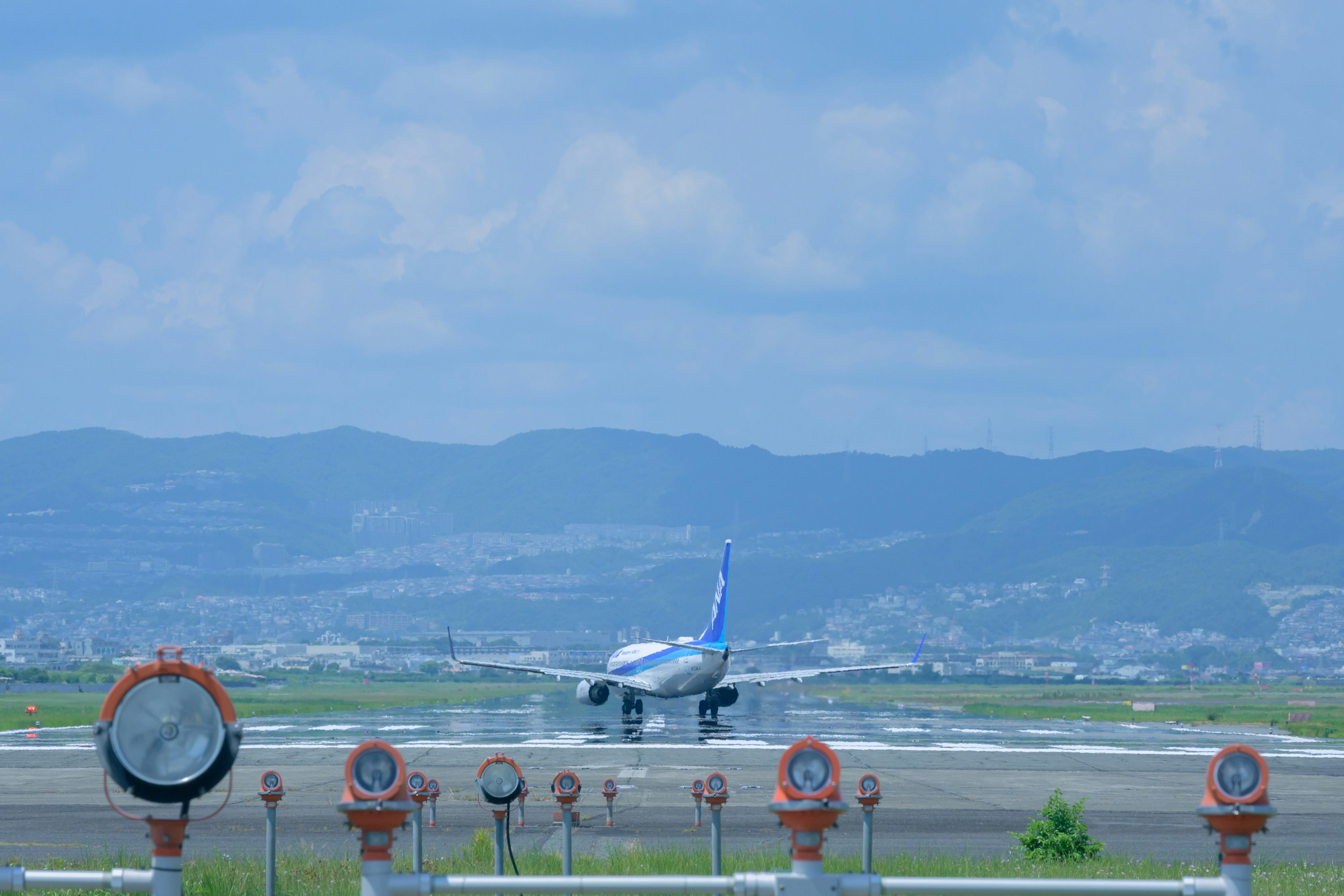 青い空の下で滑走路を離れる飛行機と滑走路灯