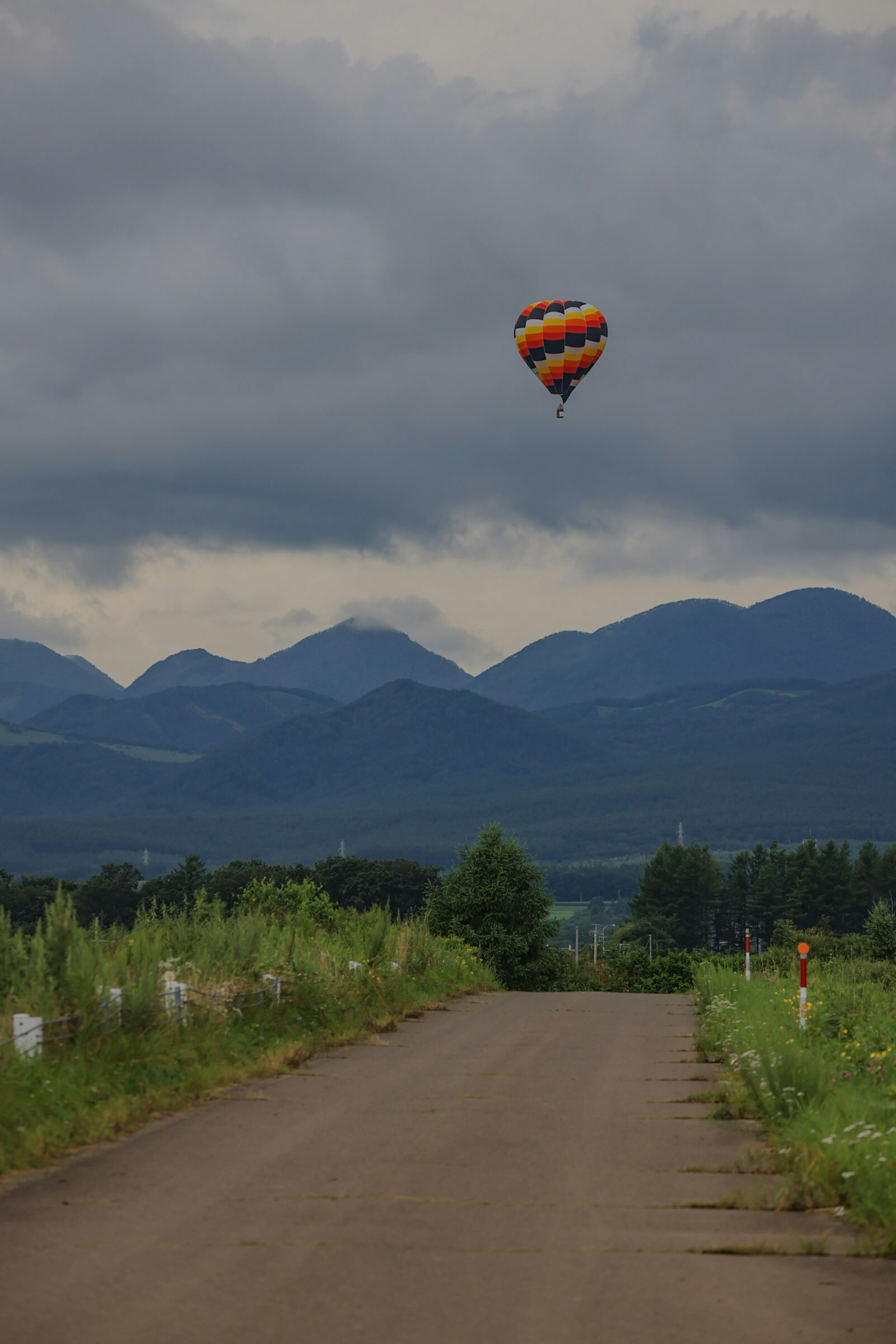 Montgolfière orange et noire flottant dans le ciel avec des montagnes en arrière-plan