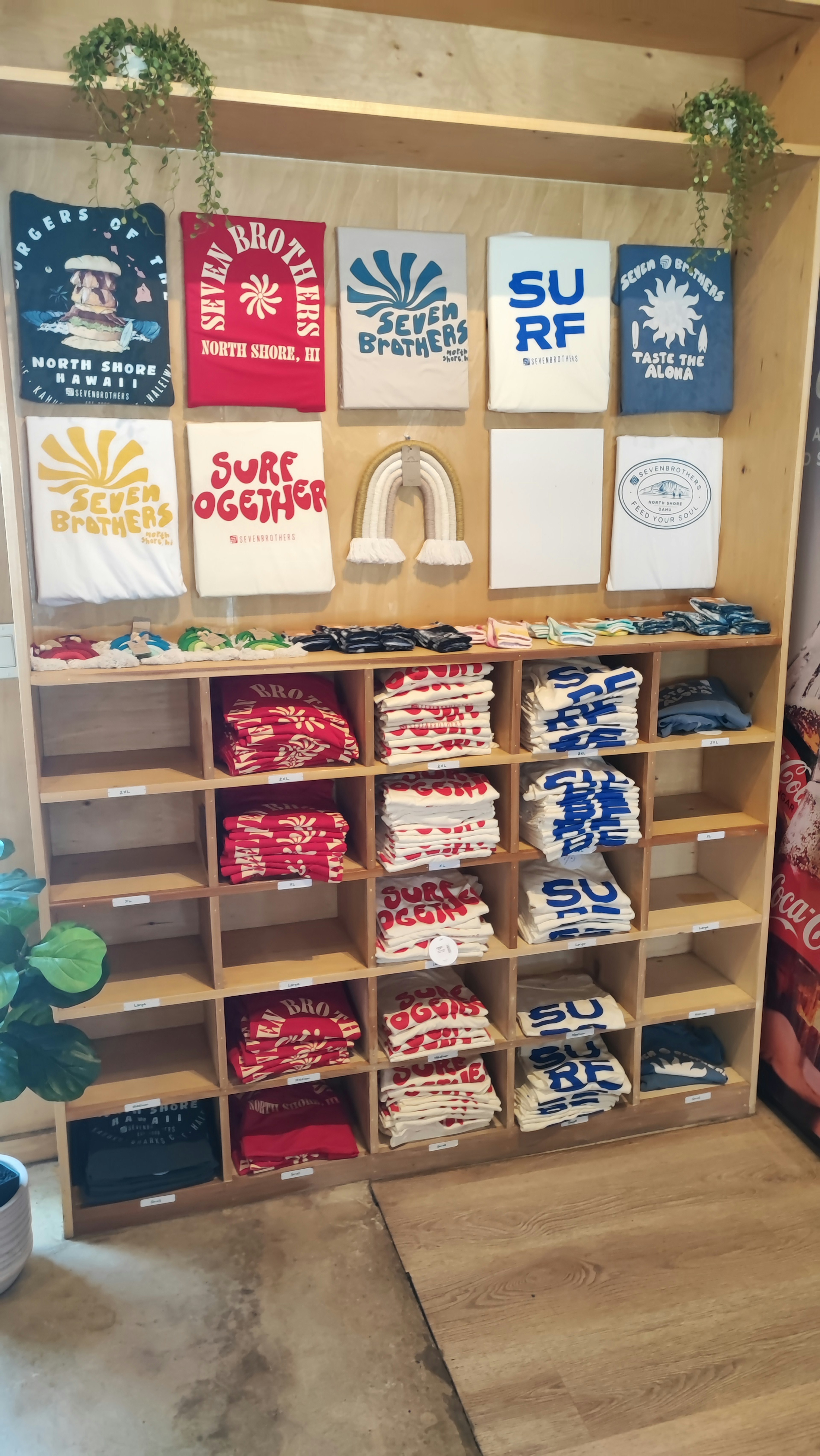 Wooden shelf displaying colorful T-shirts with various printed designs above