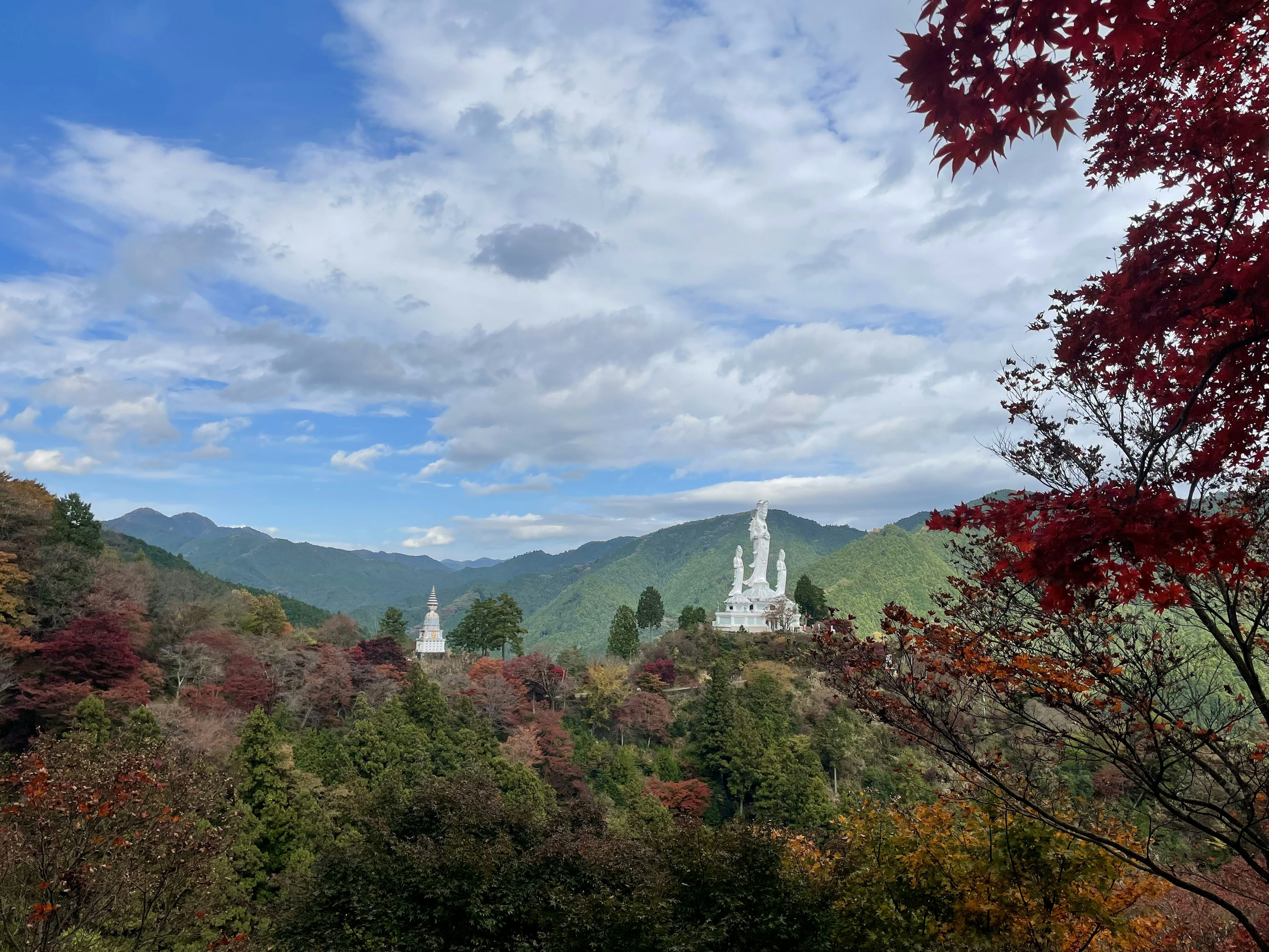 美しい山々を背景にした白い仏塔と色づいた木々の風景