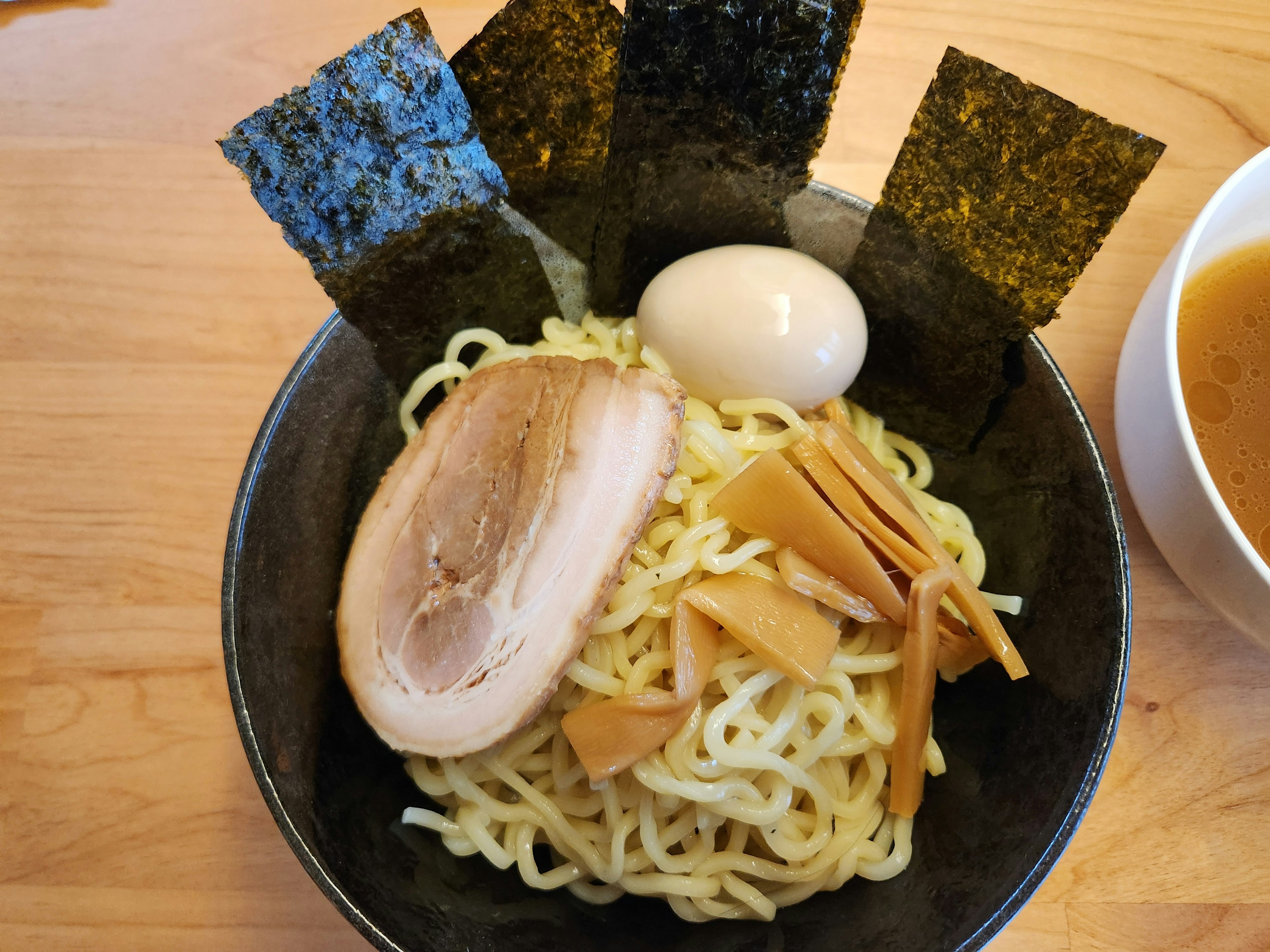 黒いボウルに盛られたつけ麺の料理　トッピングにチャーシュー　煮卵　メンマ　海苔がある