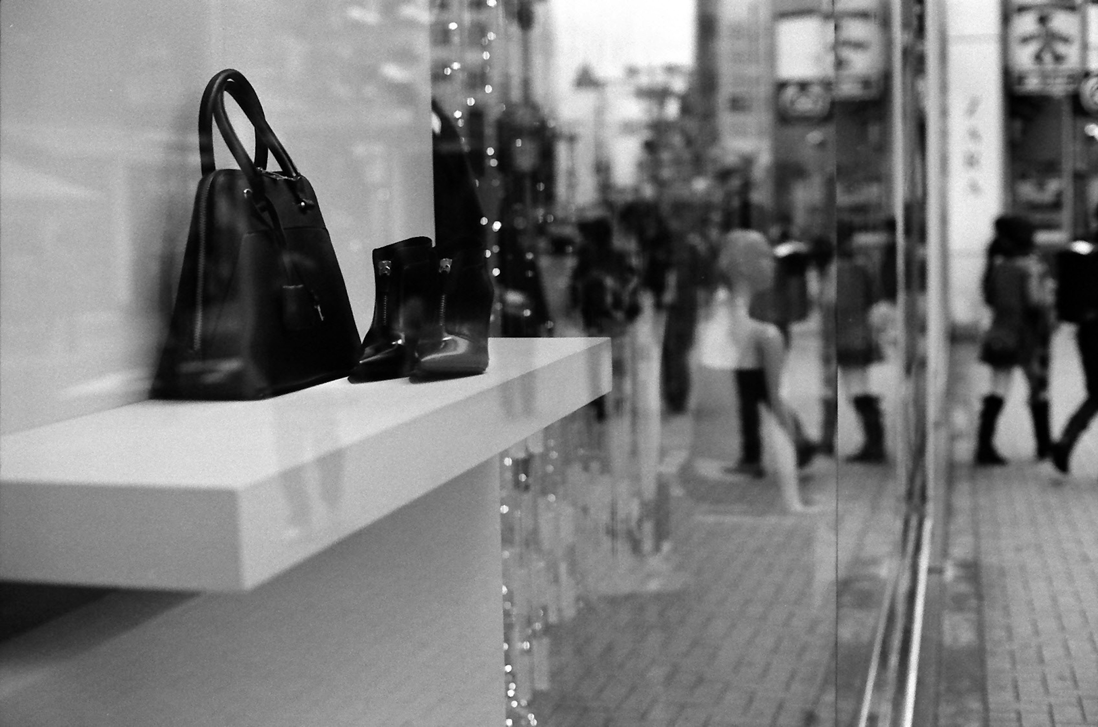 Black bags and shoes displayed in a shop window with people walking by